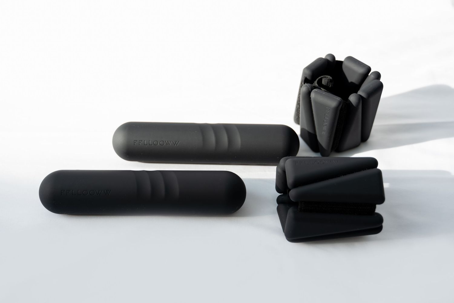 Black cylindrical objects casting dramatic shadows on a white surface.