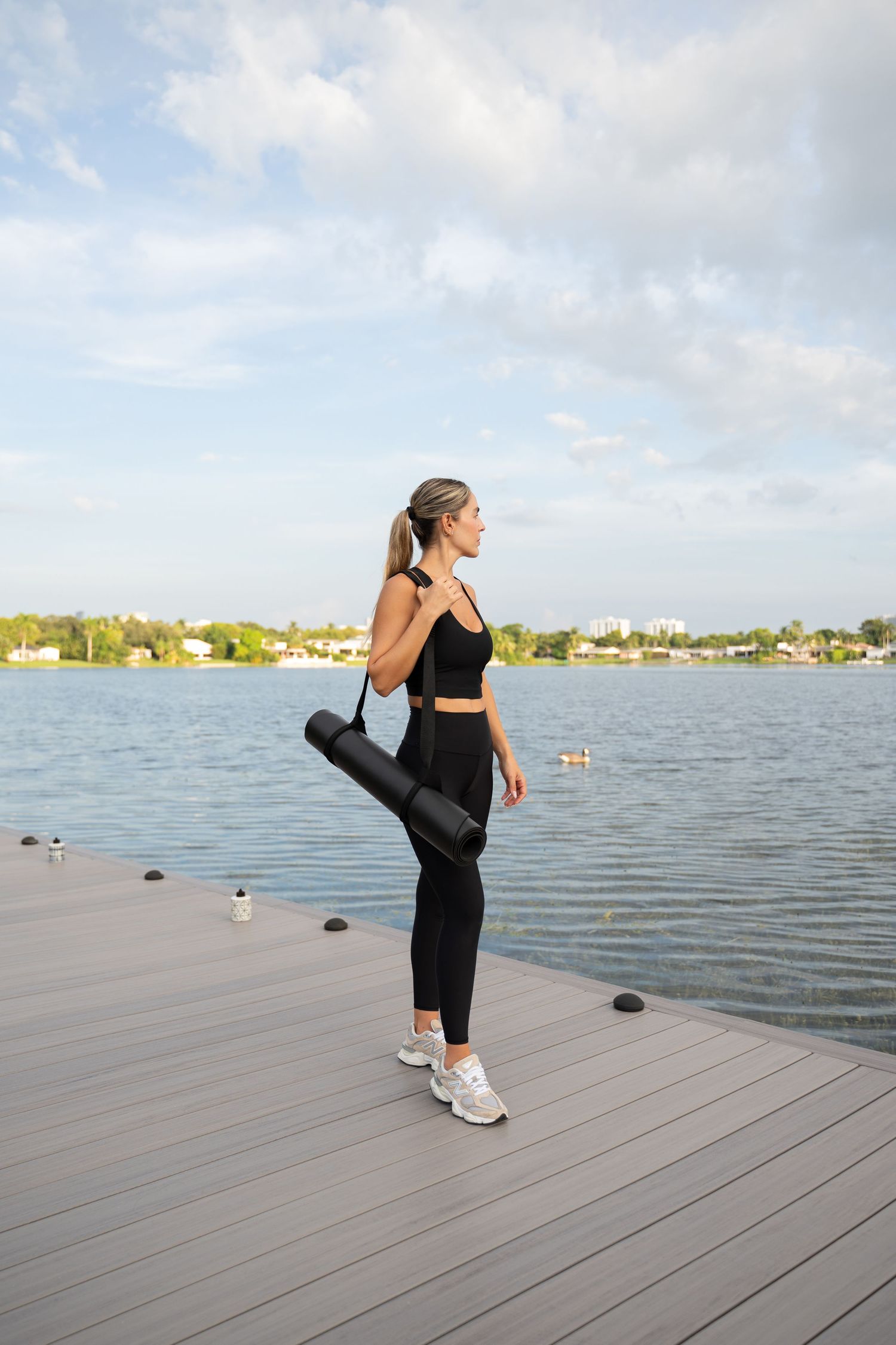 Person in athletic wear stretching on a wooden dock by a lake.