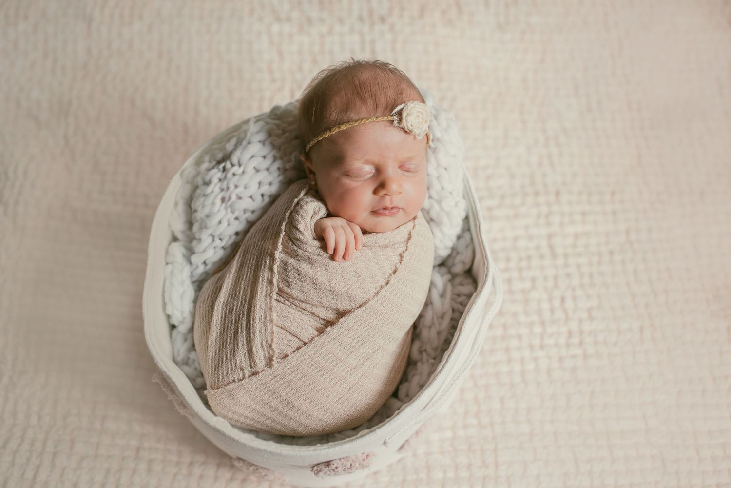 A series of peaceful newborn photography portraits showing a sleeping baby wrapped in soft beige fabric on textured backgrounds.