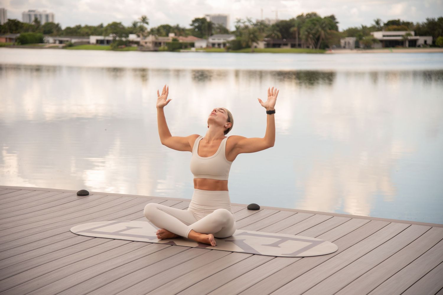 Yoga practitioner in white performing poses on lakeside wooden deck.