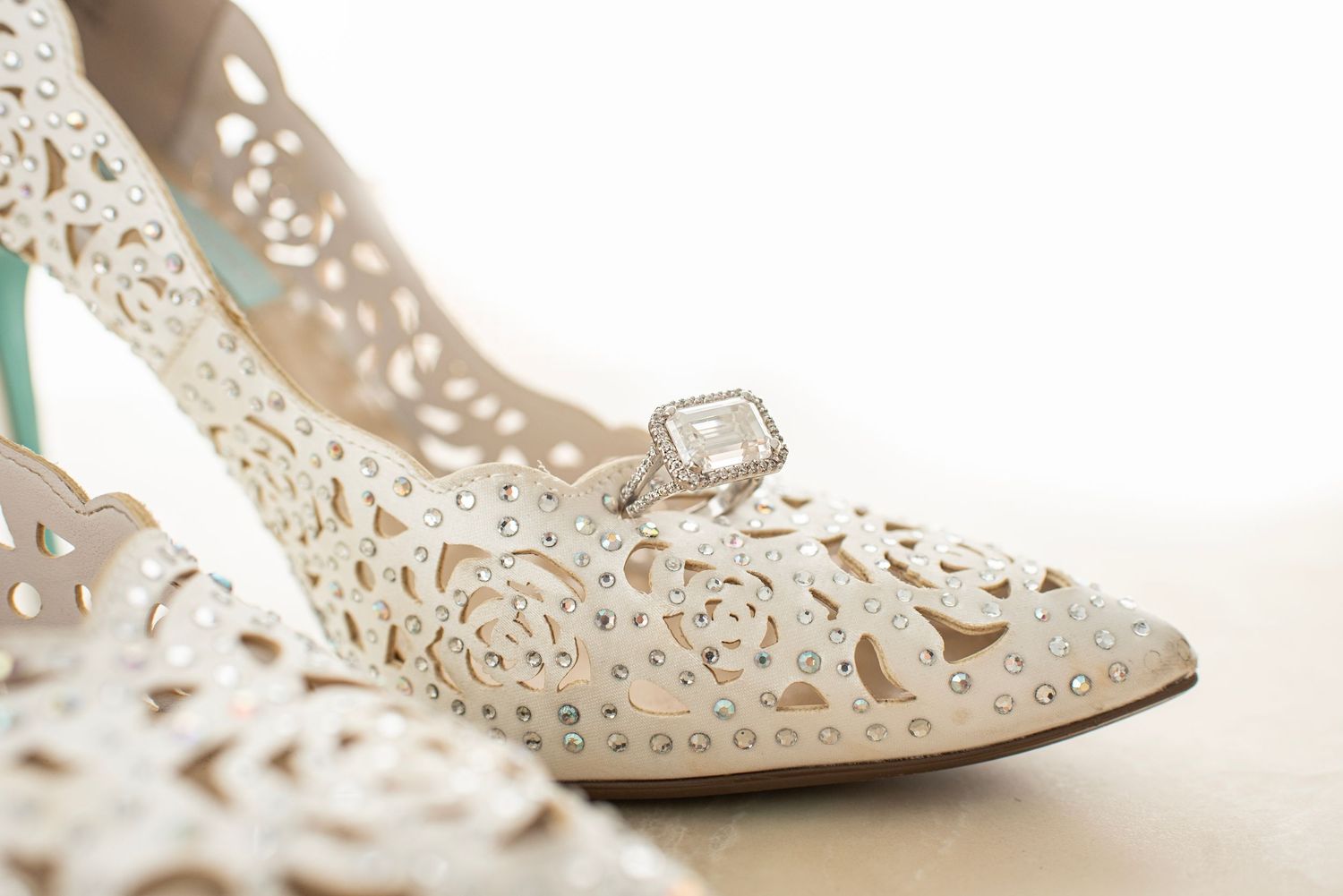 Delicate white lace bridal shoe with intricate cutout details and crystal embellishment.
