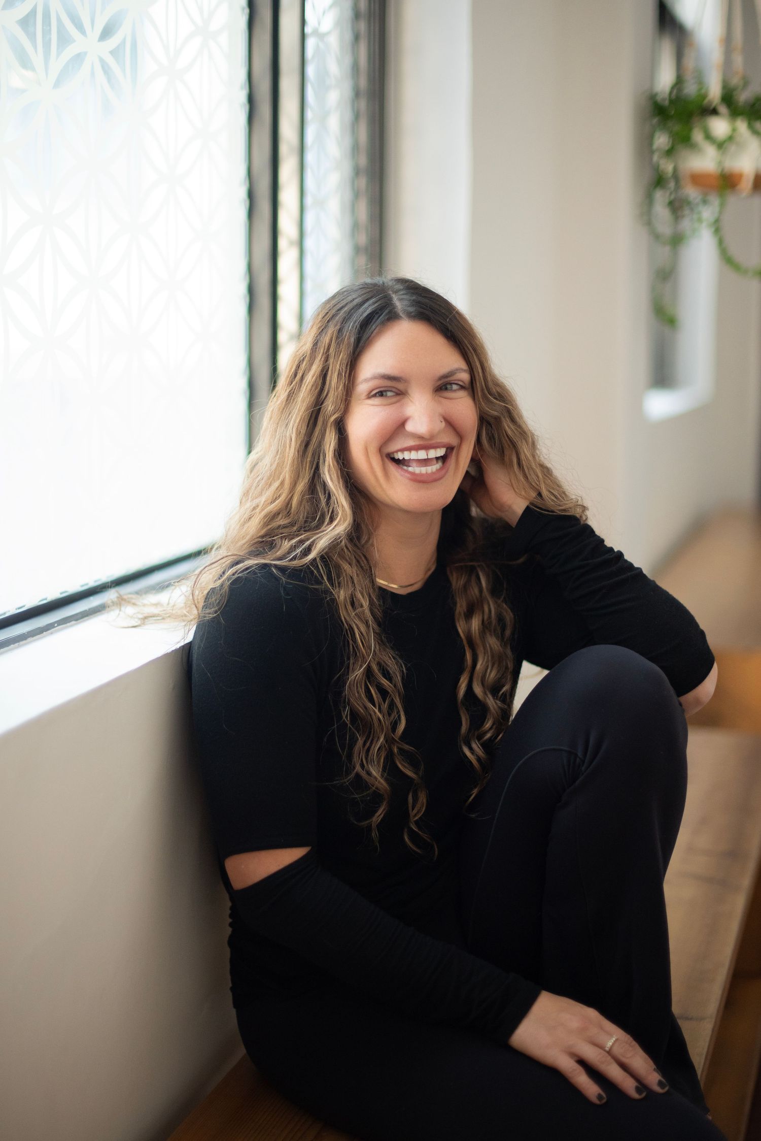 A series of candid portraits showing joyful expressions and laughter while wearing a black top near a window.