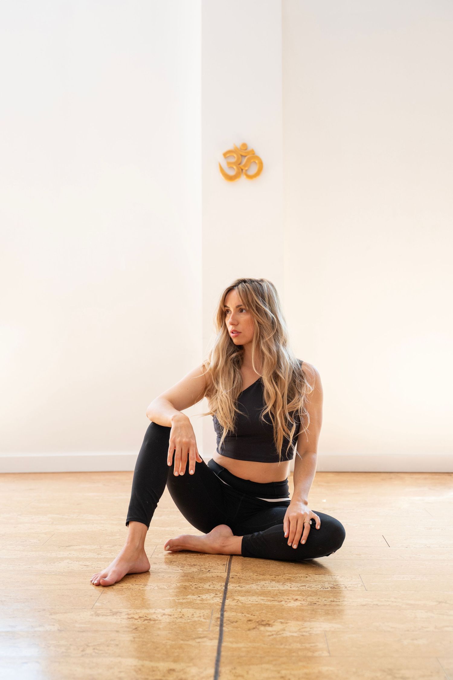 Dancer performs a graceful stretching sequence on wooden floor in minimalist white studio space.