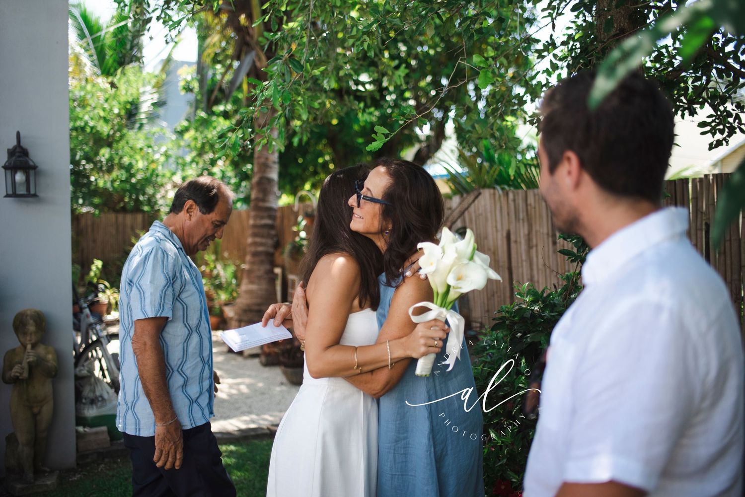 People in white and blue attire posing playfully in lush garden setting.
