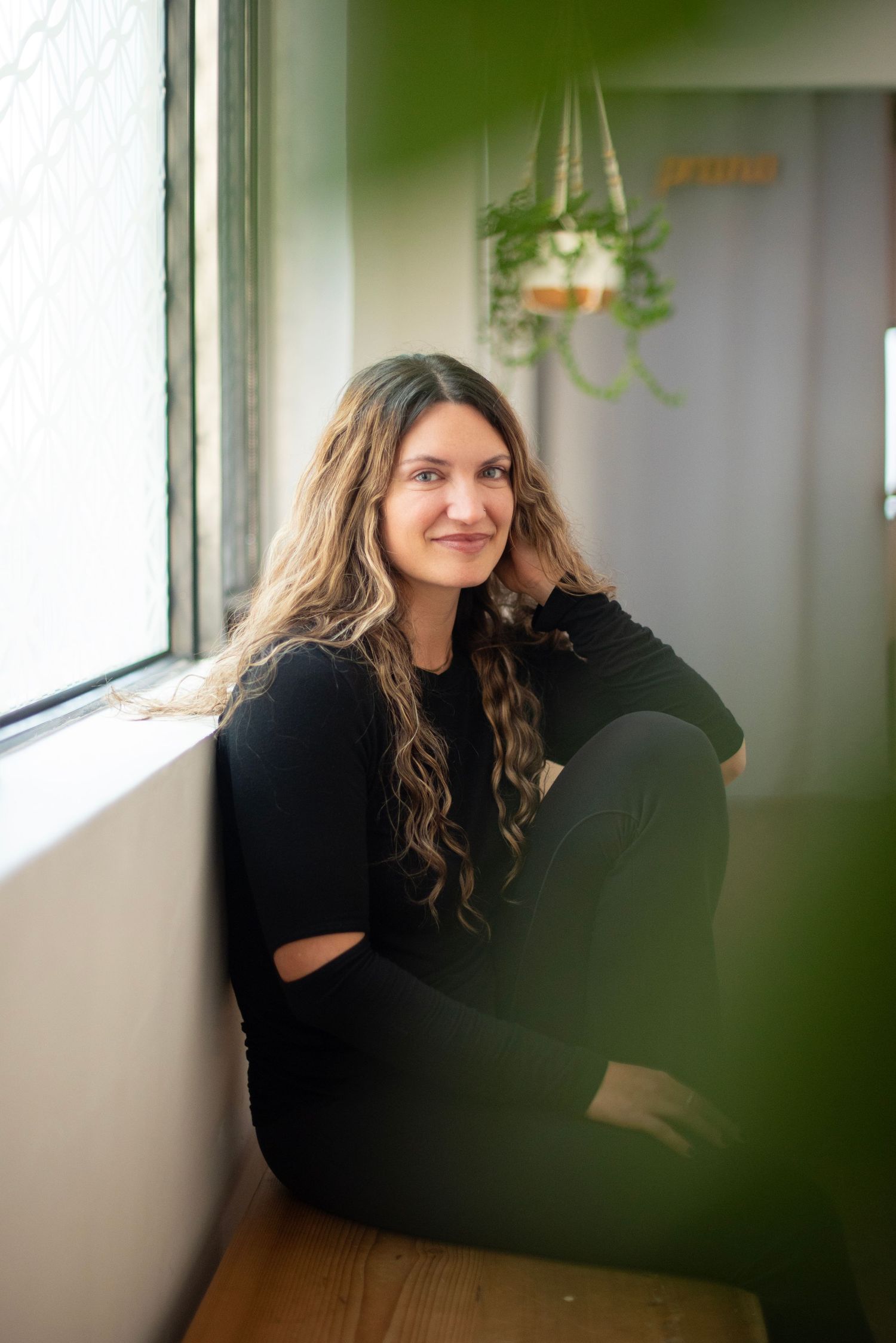 A person in a black sweater sits near a window in a series of candid portrait shots.