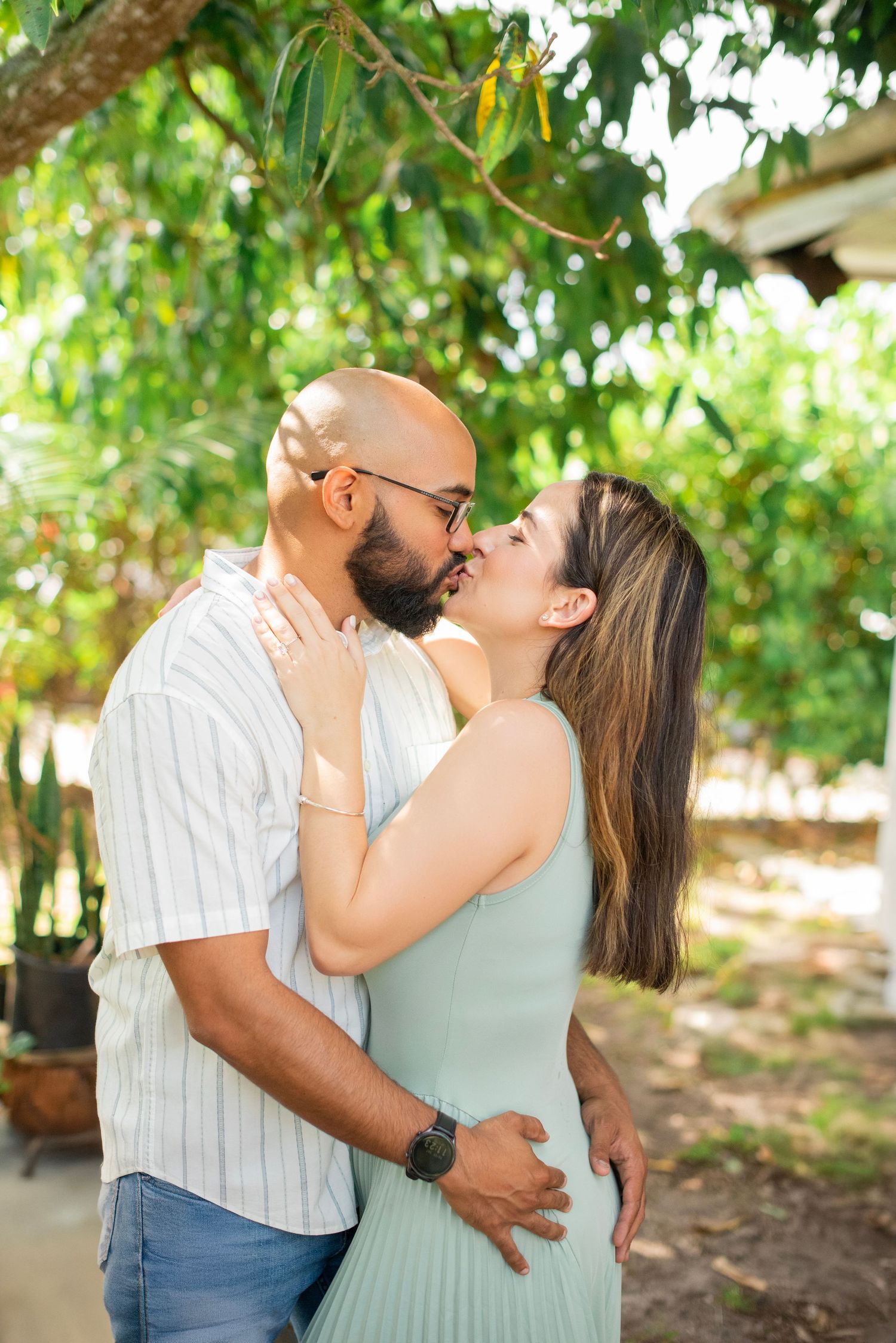 Romantic couple sharing tender moments in a lush garden setting with green foliage in the background.