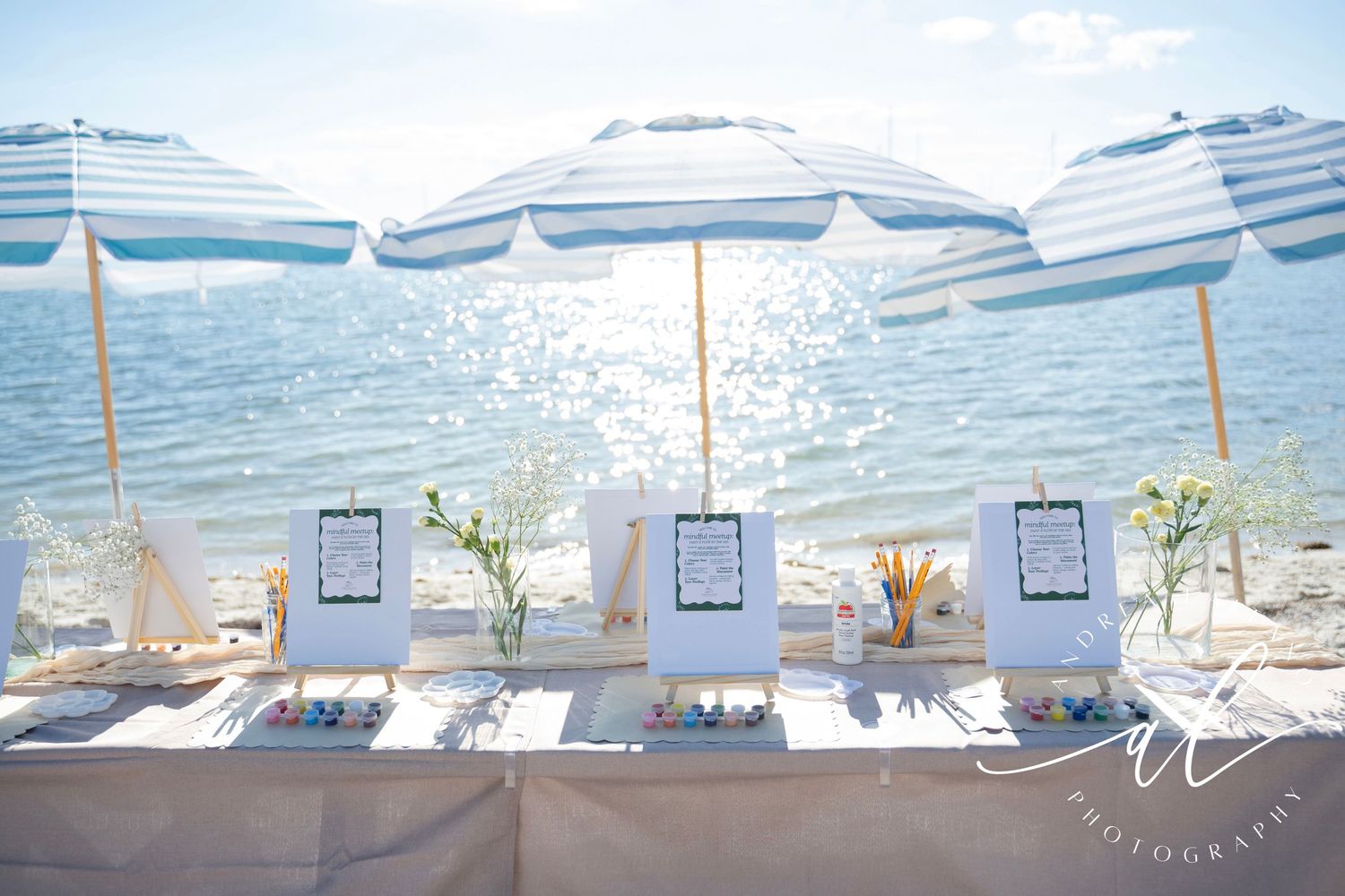 Coastal beach lounge chairs with blue and white striped umbrellas arranged along a tranquil shoreline.