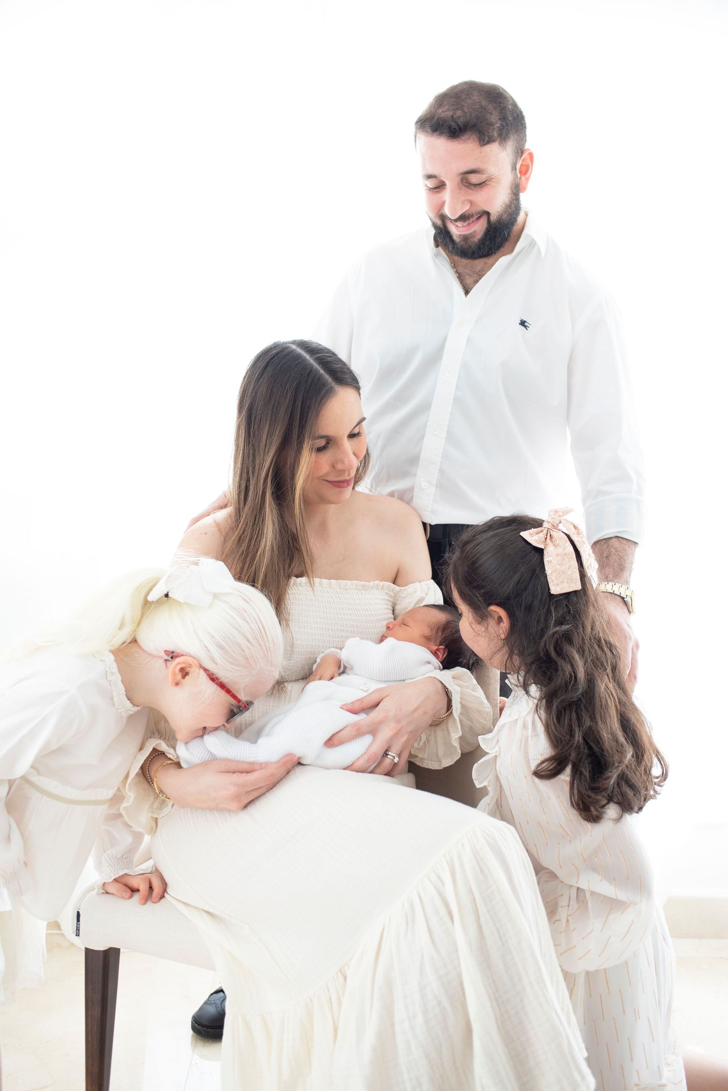 Family shares intimate moment together while dressed in coordinating white outfits.