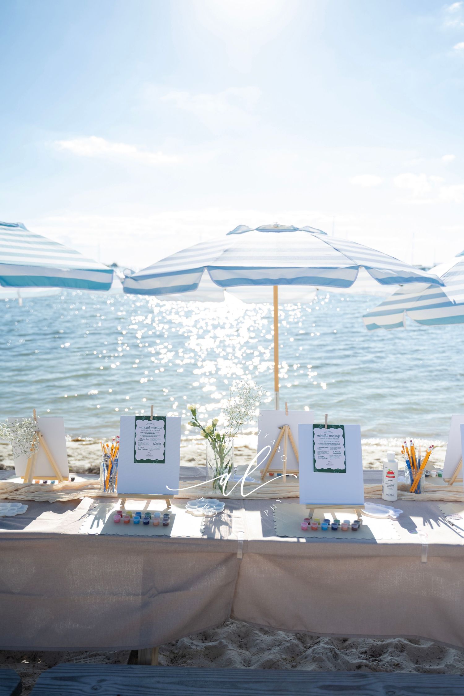 White beach umbrellas and lounge chairs line a pristine oceanfront setting with sparkling water views.