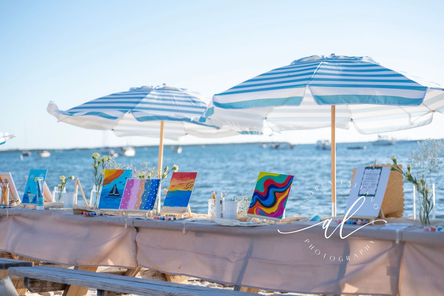 Blue and white striped beach umbrellas line a sandy shore with calm ocean waters in the background.