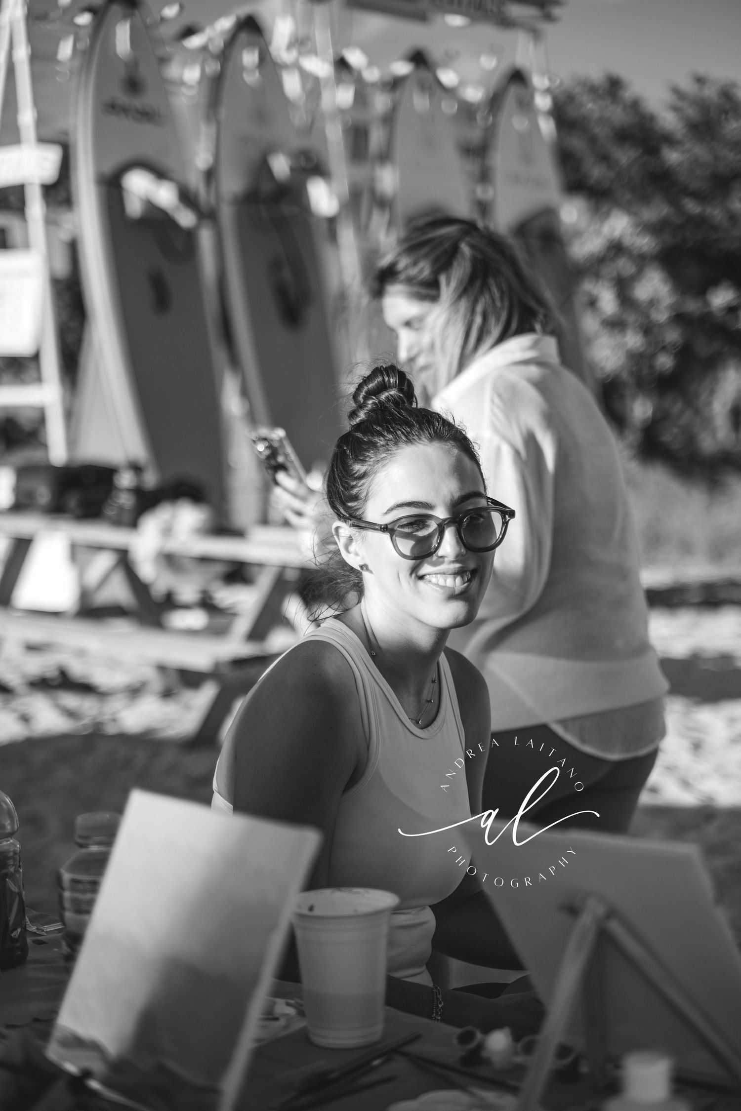 A series of black and white photos showing someone smiling while wearing sunglasses and working on a laptop outdoors.