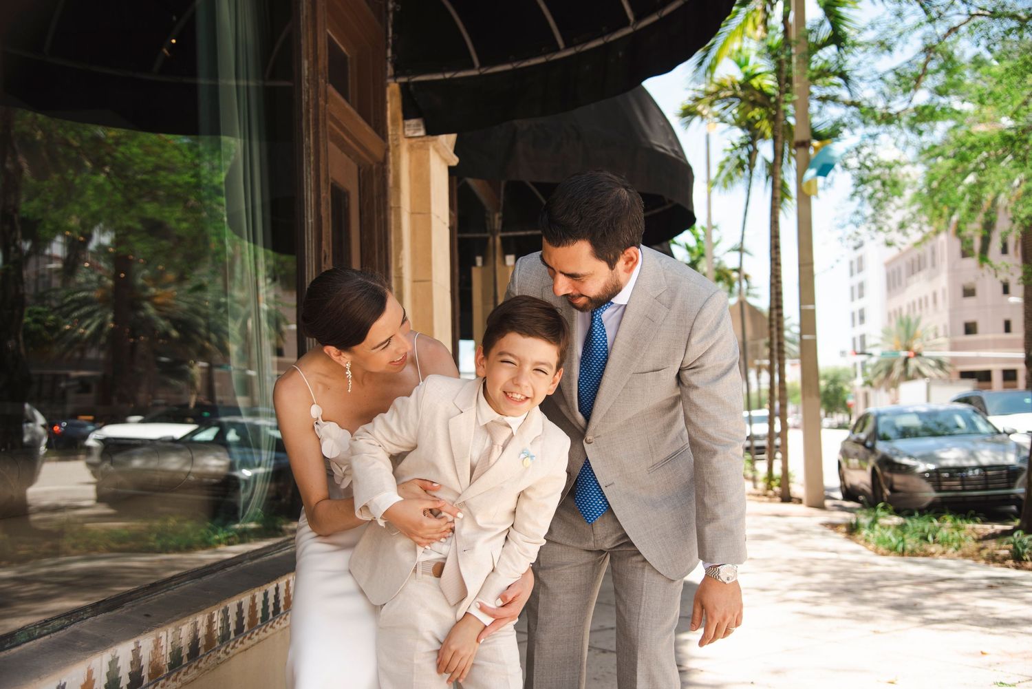 Two people walking together outdoors on a sunny day wearing light colored formal attire.
