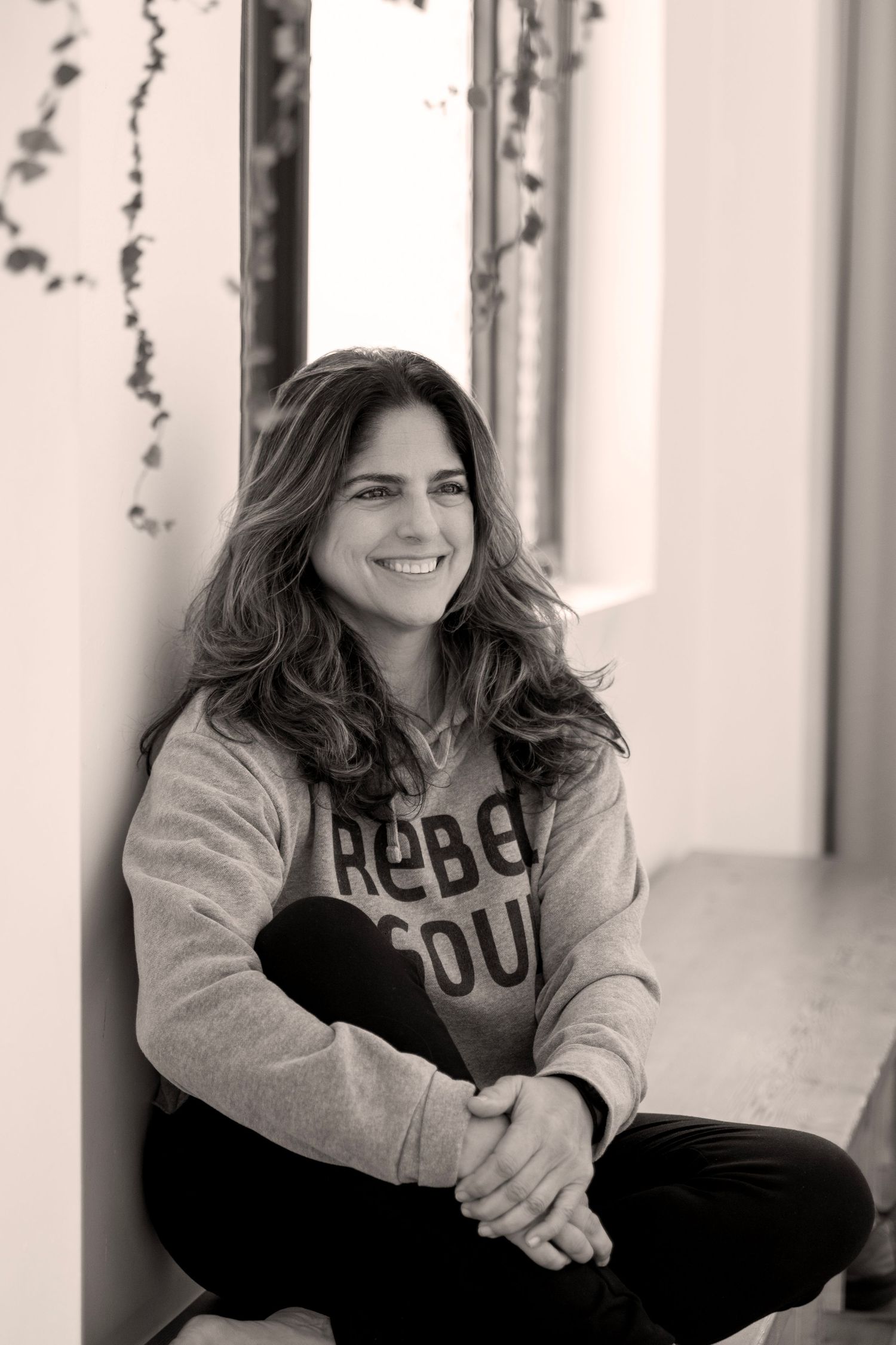 A series of black and white portraits showing someone in a casual sweatshirt sitting and smiling in different poses.