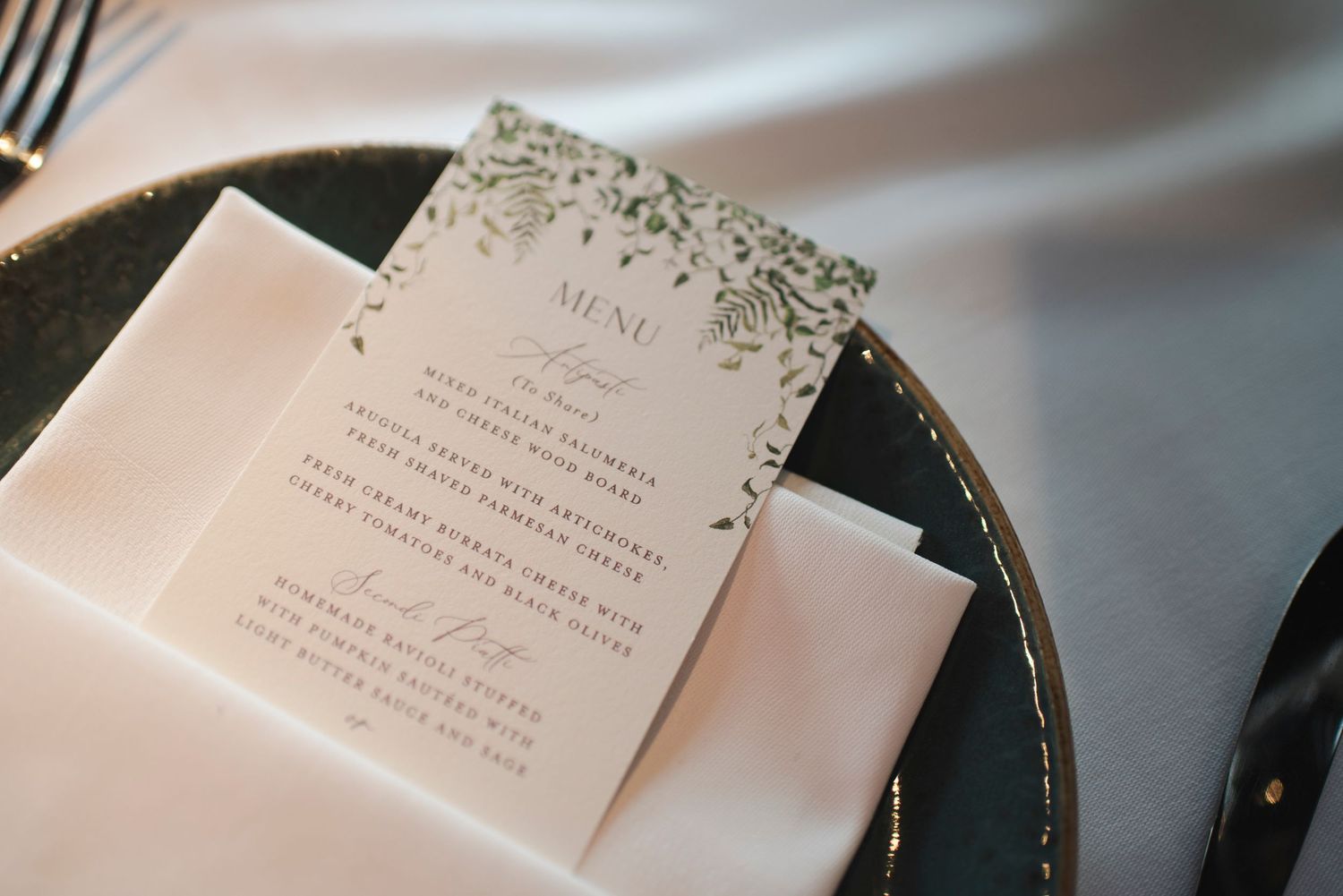 Wedding invitation cards displayed on dark plates with elegant typography.