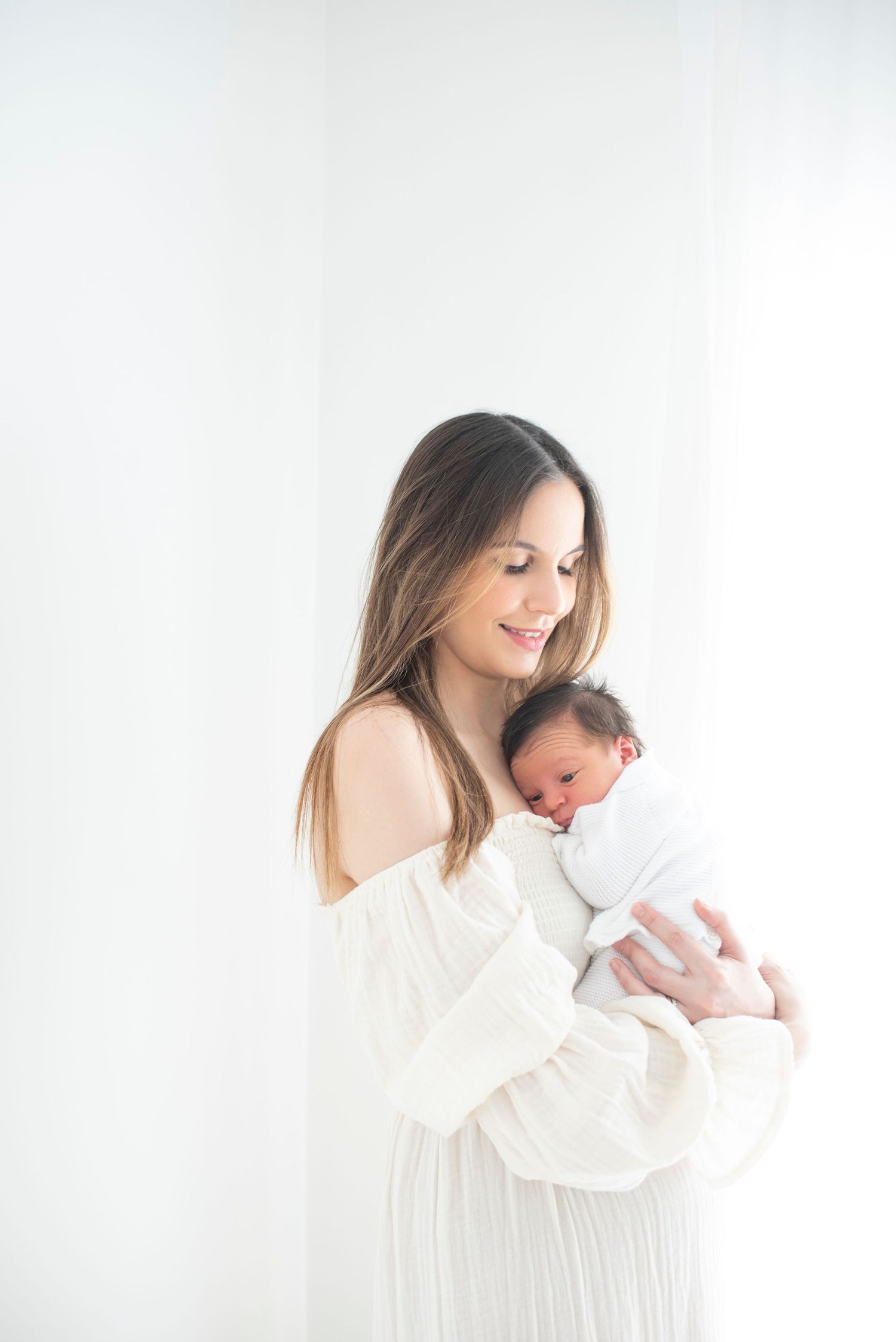 Gentle embrace captured in soft white tones against minimalist background.