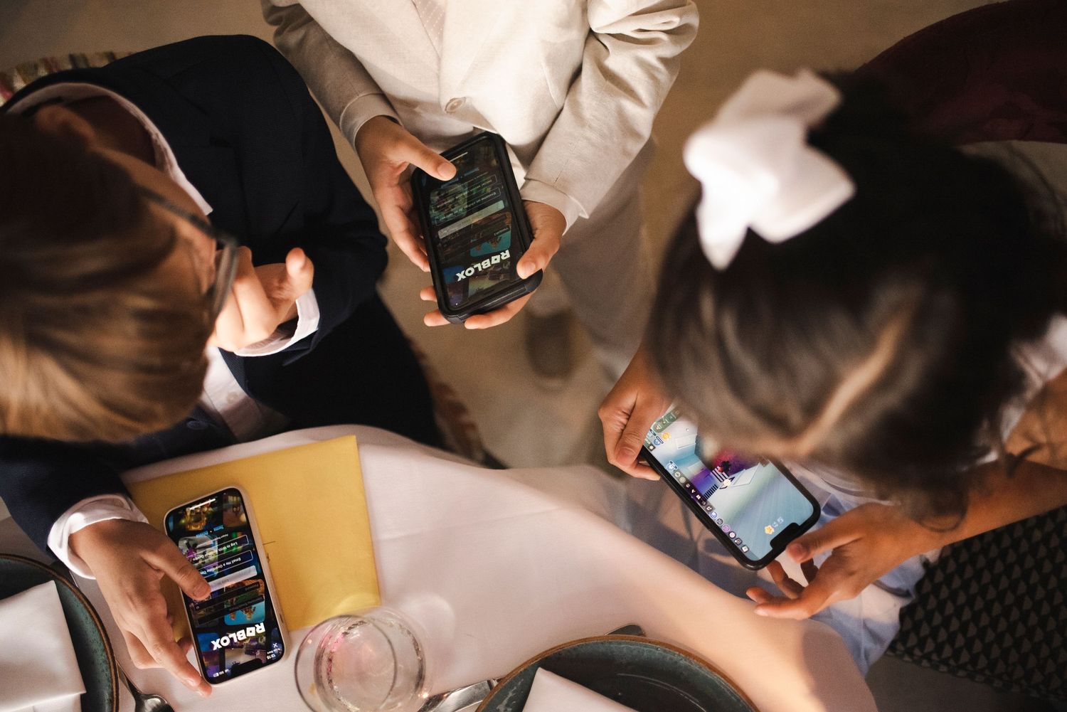 Overhead view of people using mobile phones around a table.