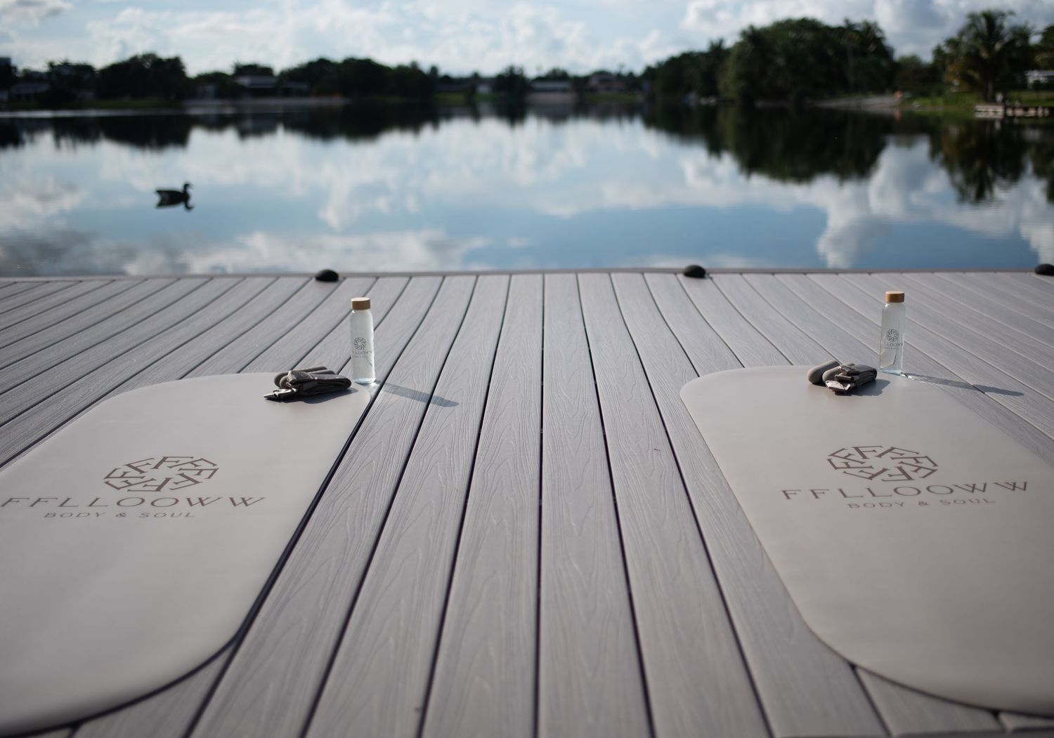 Wooden dock extending over calm lake waters with cloudy sky reflections.