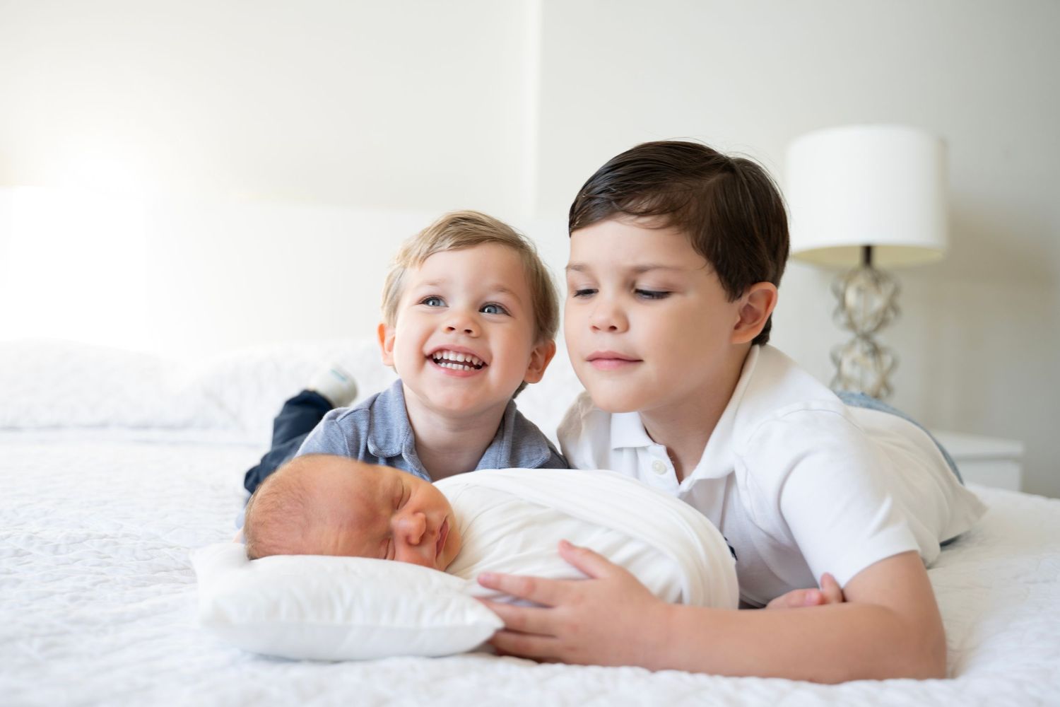 A series of tender family moments showing parents and children snuggling together in white bedding.