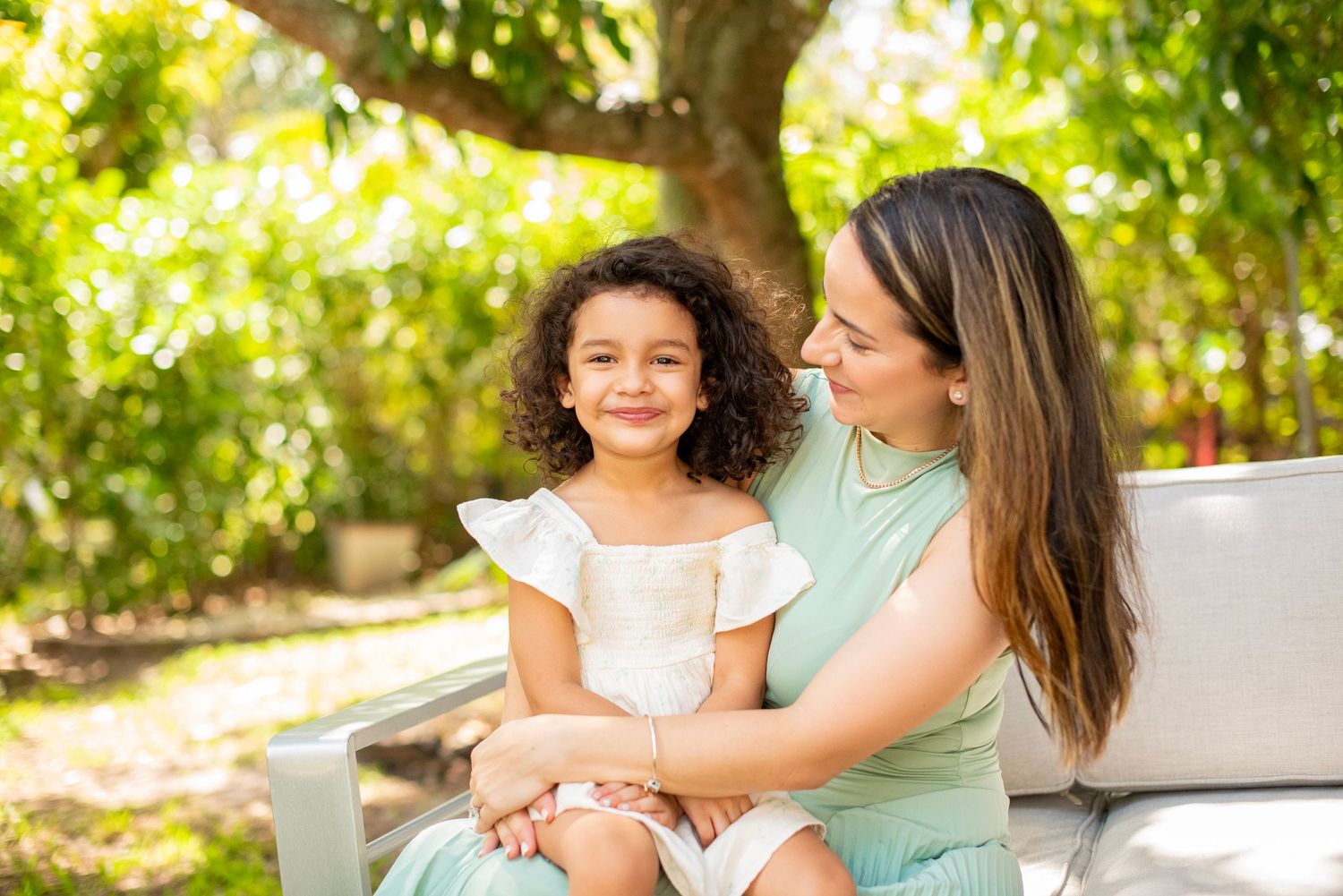 A series of candid outdoor family photos showing tender moments between parent and child in a sunlit garden setting.