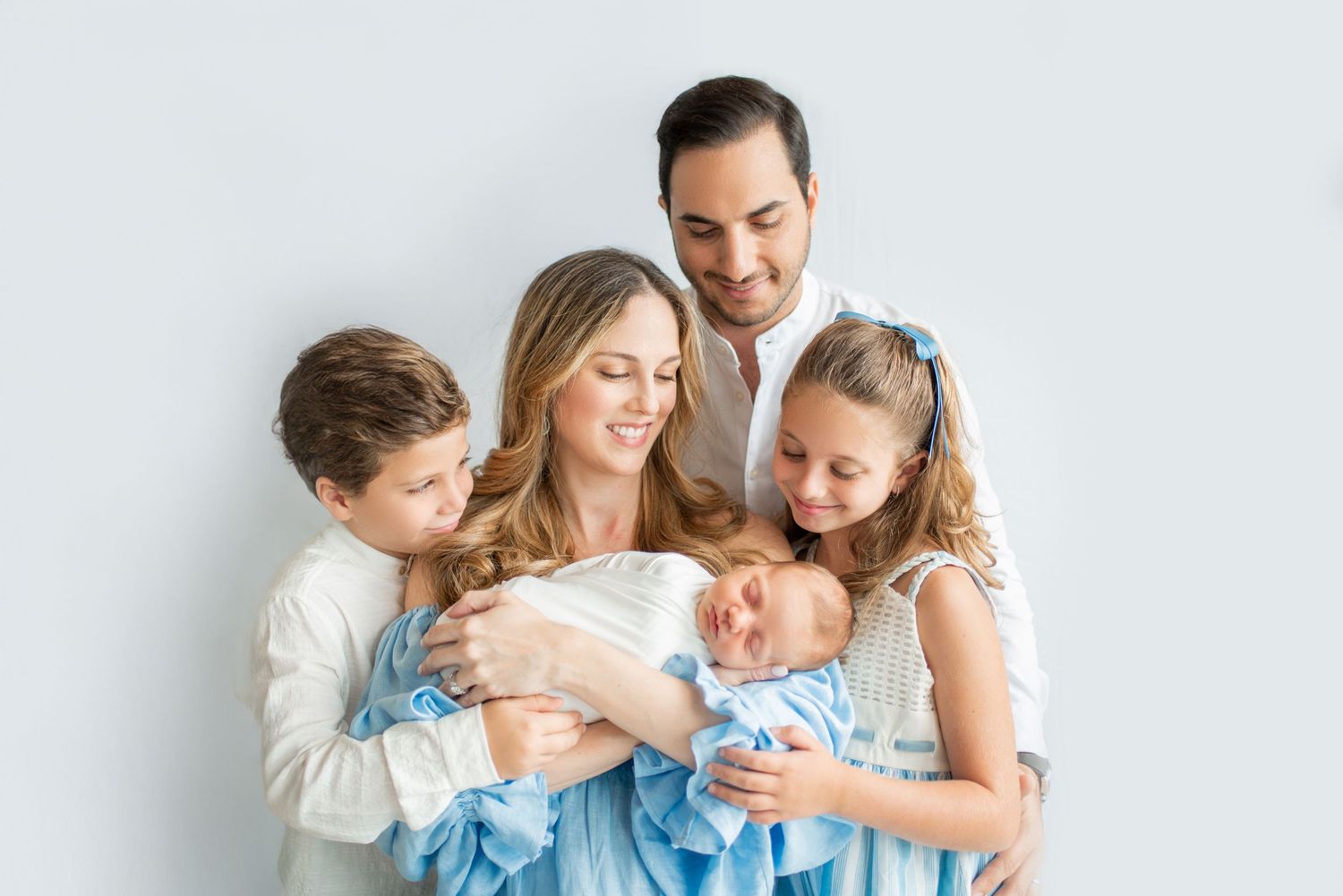 Joyful family embracing in matching blue and white attire.