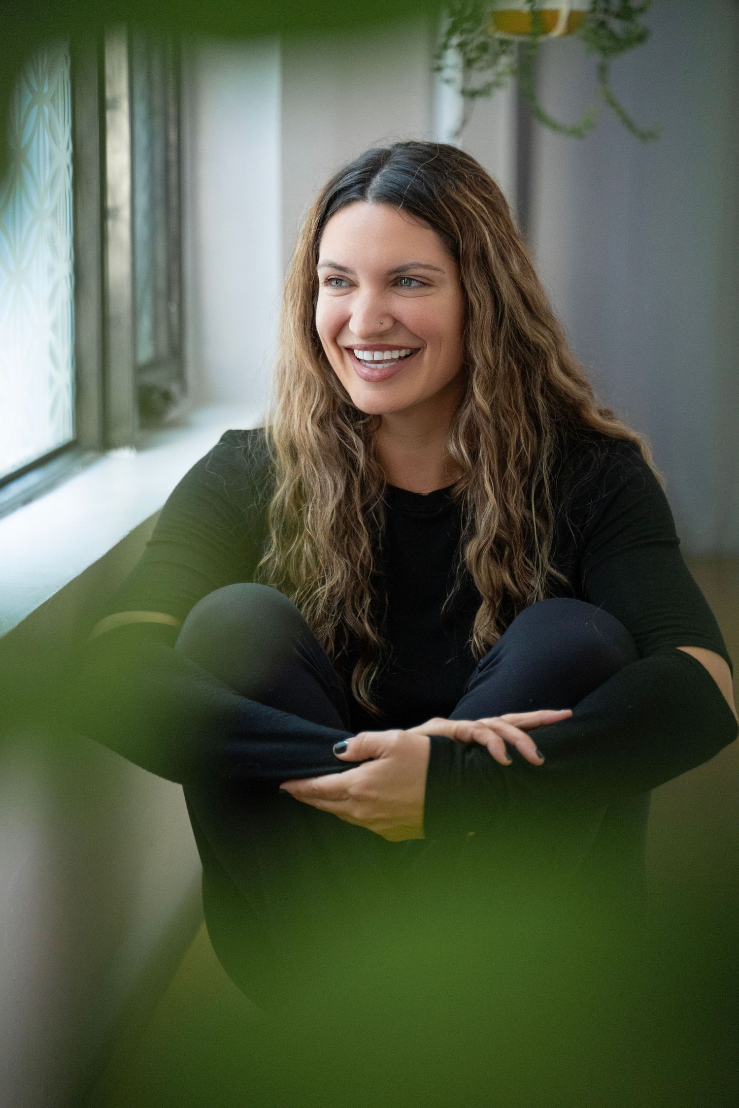 A series of portraits showing someone in a black sweater smiling by a window with natural lighting.
