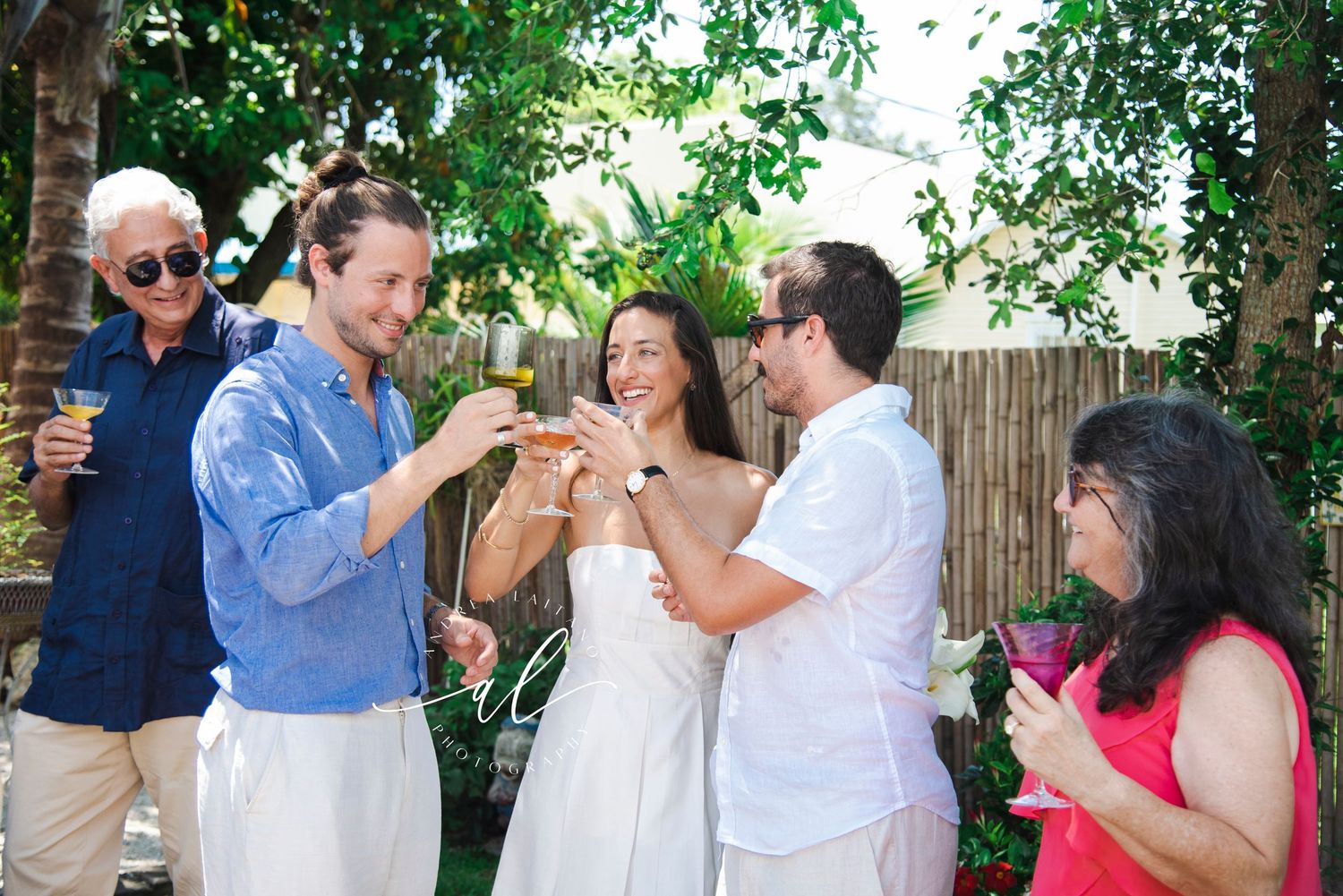 A casual outdoor celebration with guests in white and red attire against a natural garden backdrop.
