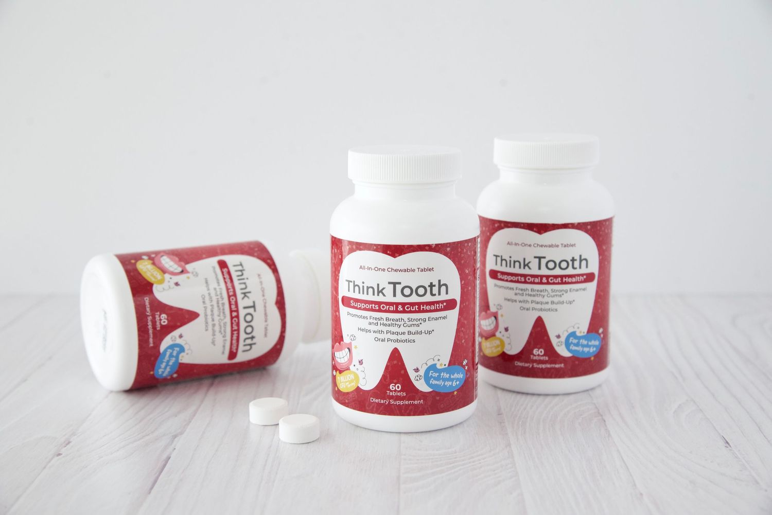 Red and white toothpaste tubes and containers arranged in a minimalist line on a white surface.