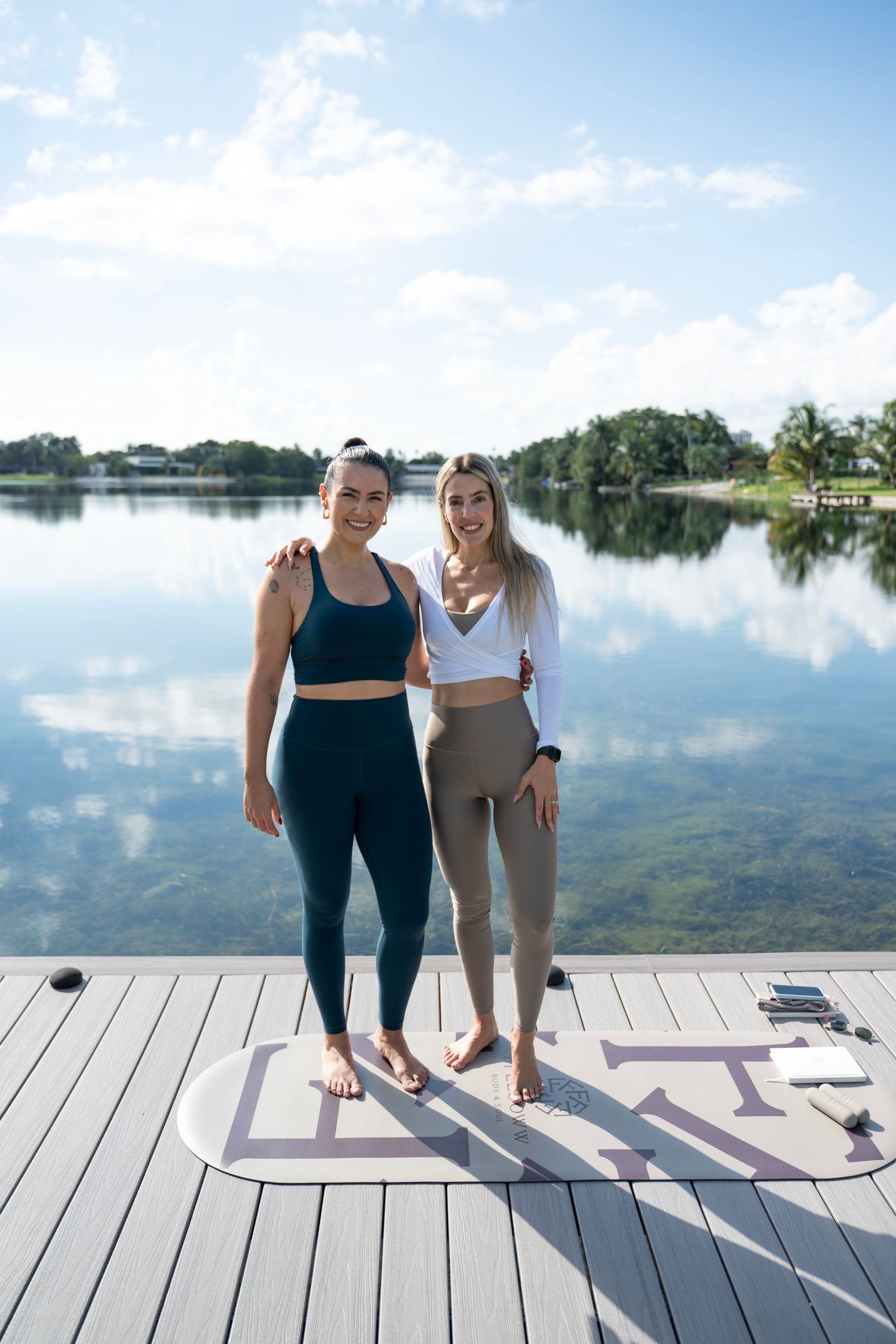 Wooden dock over tranquil lake with yoga mats laid out for outdoor exercise.