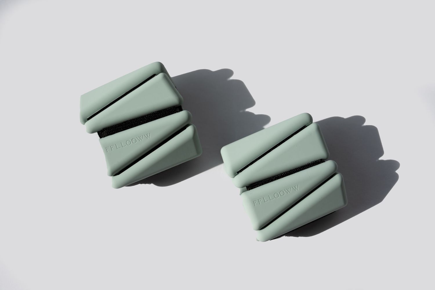 Mint green foam yoga blocks casting shadows on white surface.