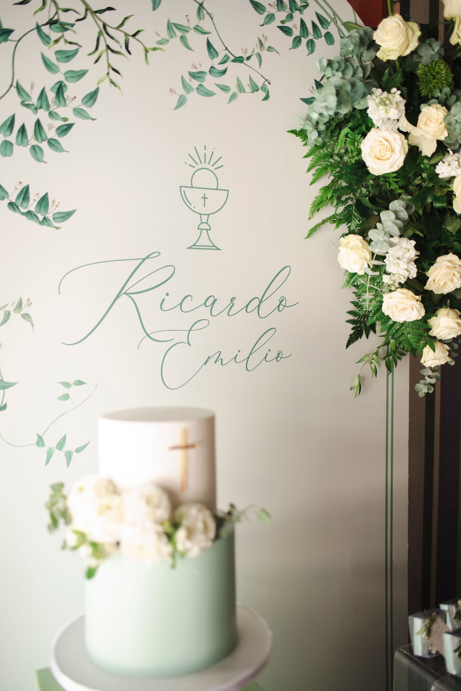 Mint green and white wedding cake decorated with floral designs and calligraphy on a white backdrop.