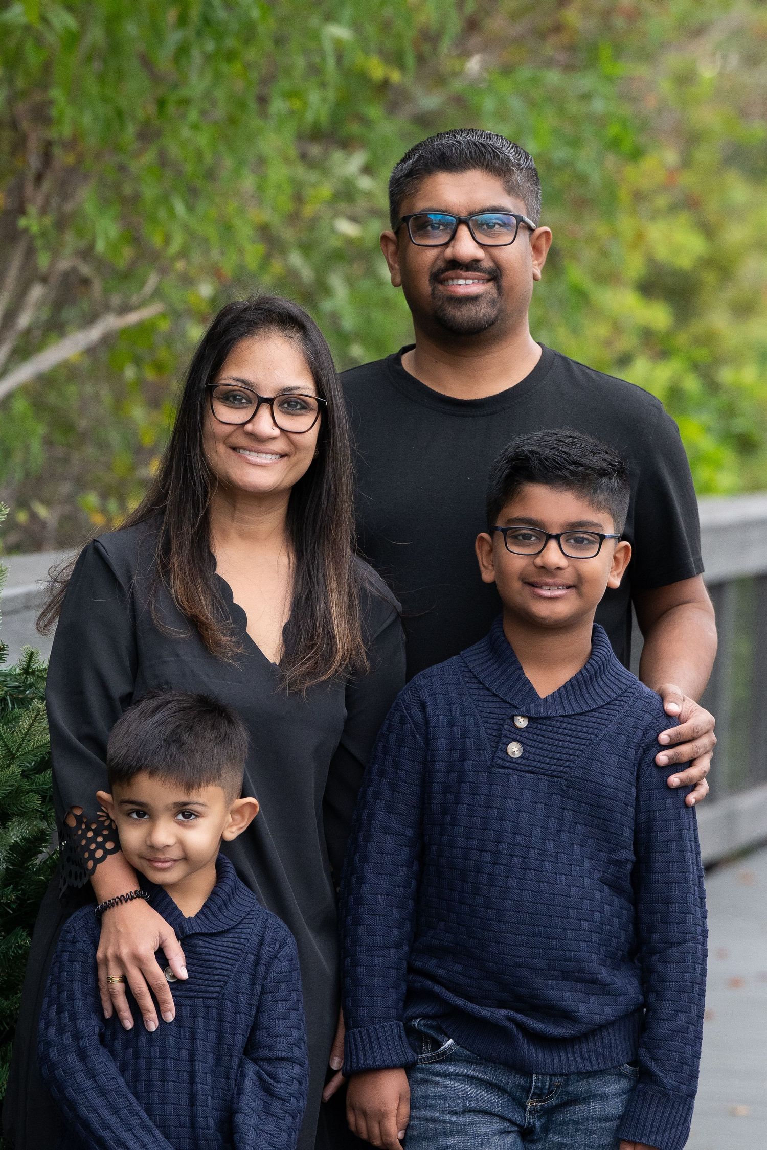A family wearing coordinated navy and black outfits poses together outdoors for portraits.