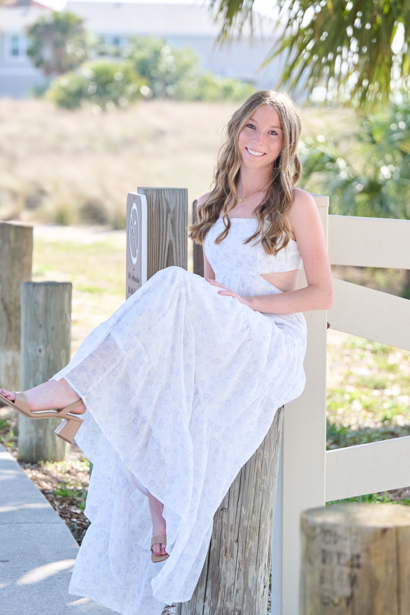 A series of outdoor portraits showing someone in a flowing white dress leaning against wooden fence posts in sunlit scenery.