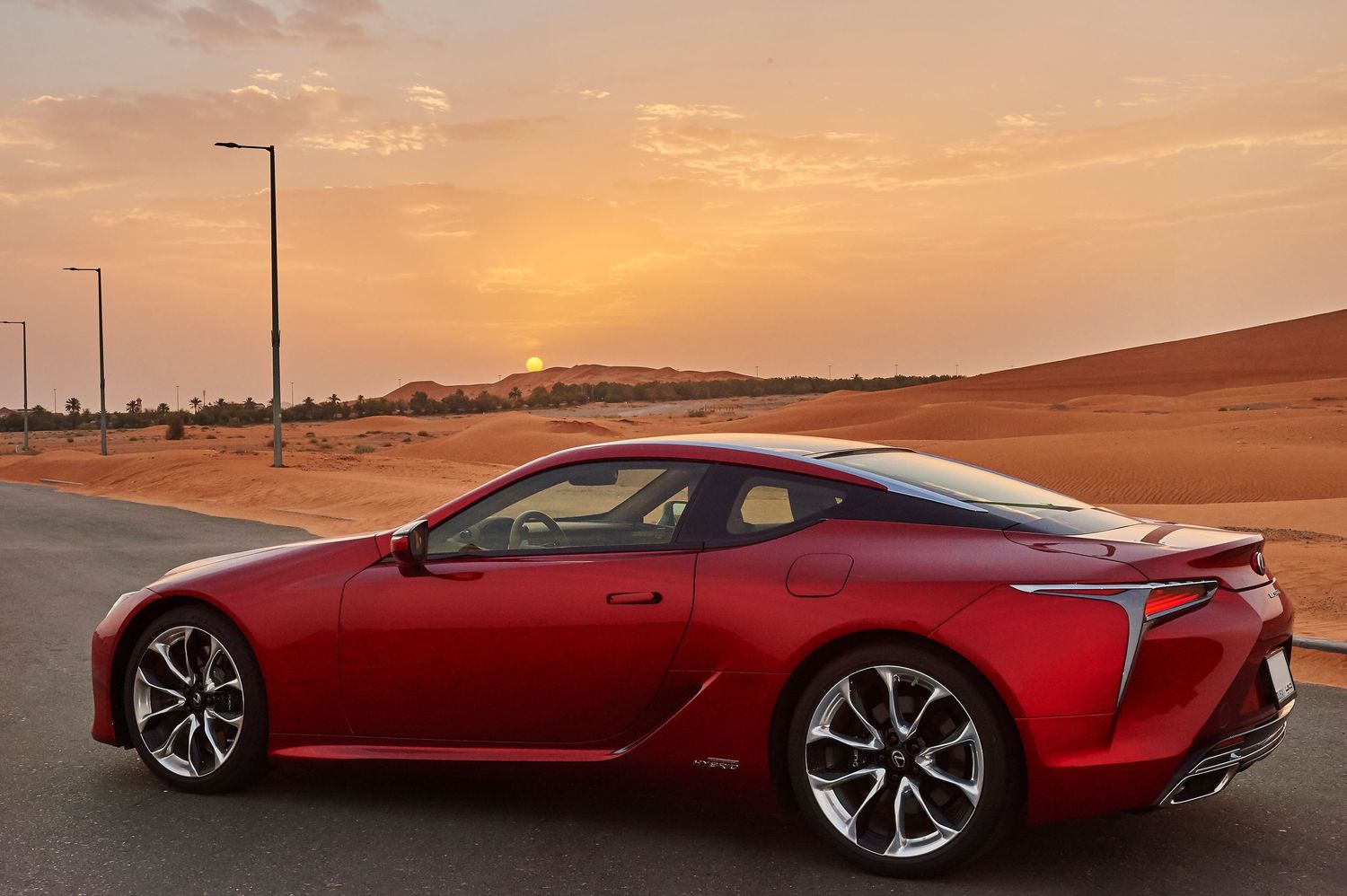 Side profile of red Lexus concept vehicle silhouetted against orange desert sky.