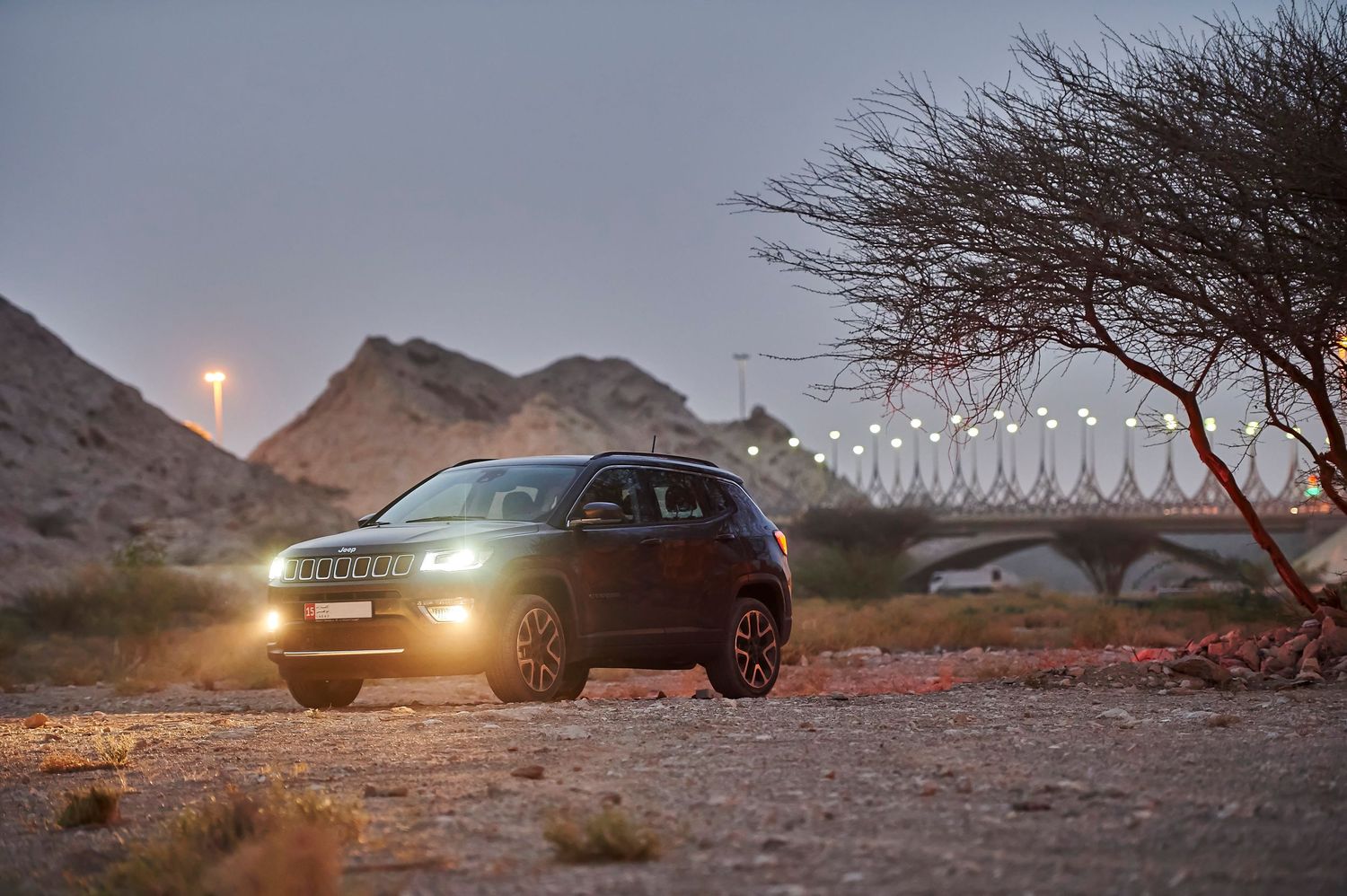 Black Jeep SUV captured during sunset against mountainous desert landscape.