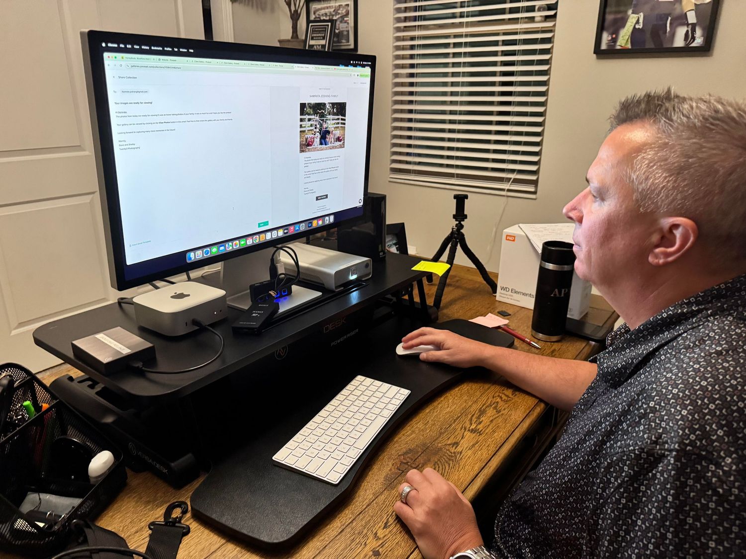 A person working at a computer setup with multiple monitors and a standing desk in a home office environment.