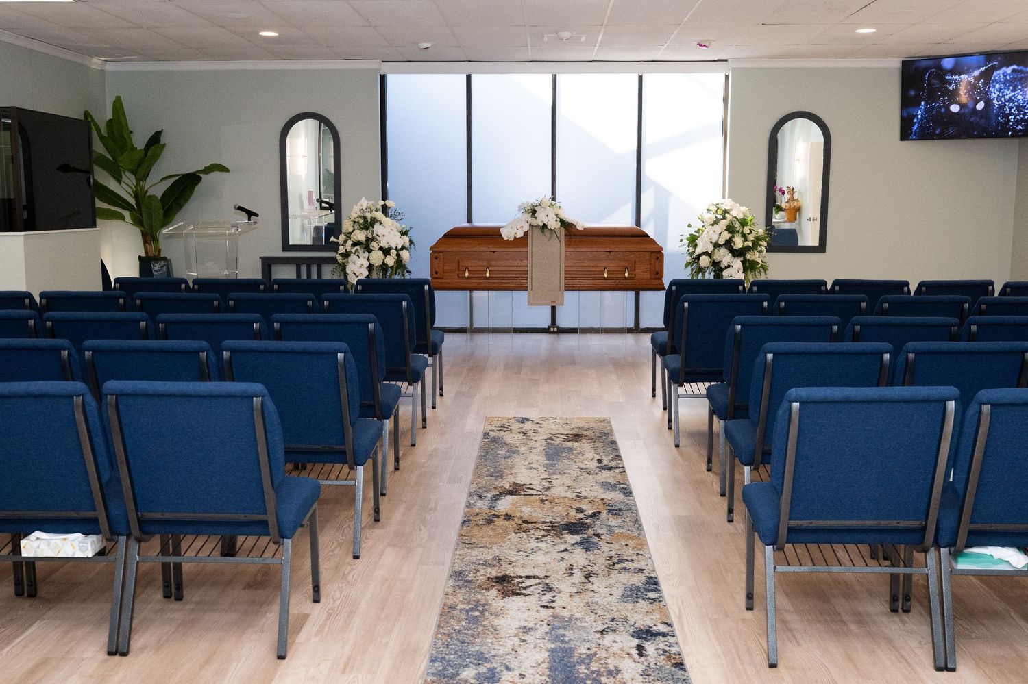 Modern church sanctuary interior with blue pews and decorative runner in the center aisle.