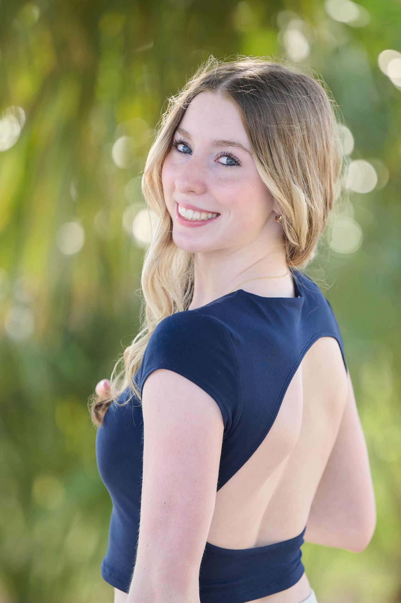 A series of photos showing someone in a navy blue top posing against a soft green natural background.