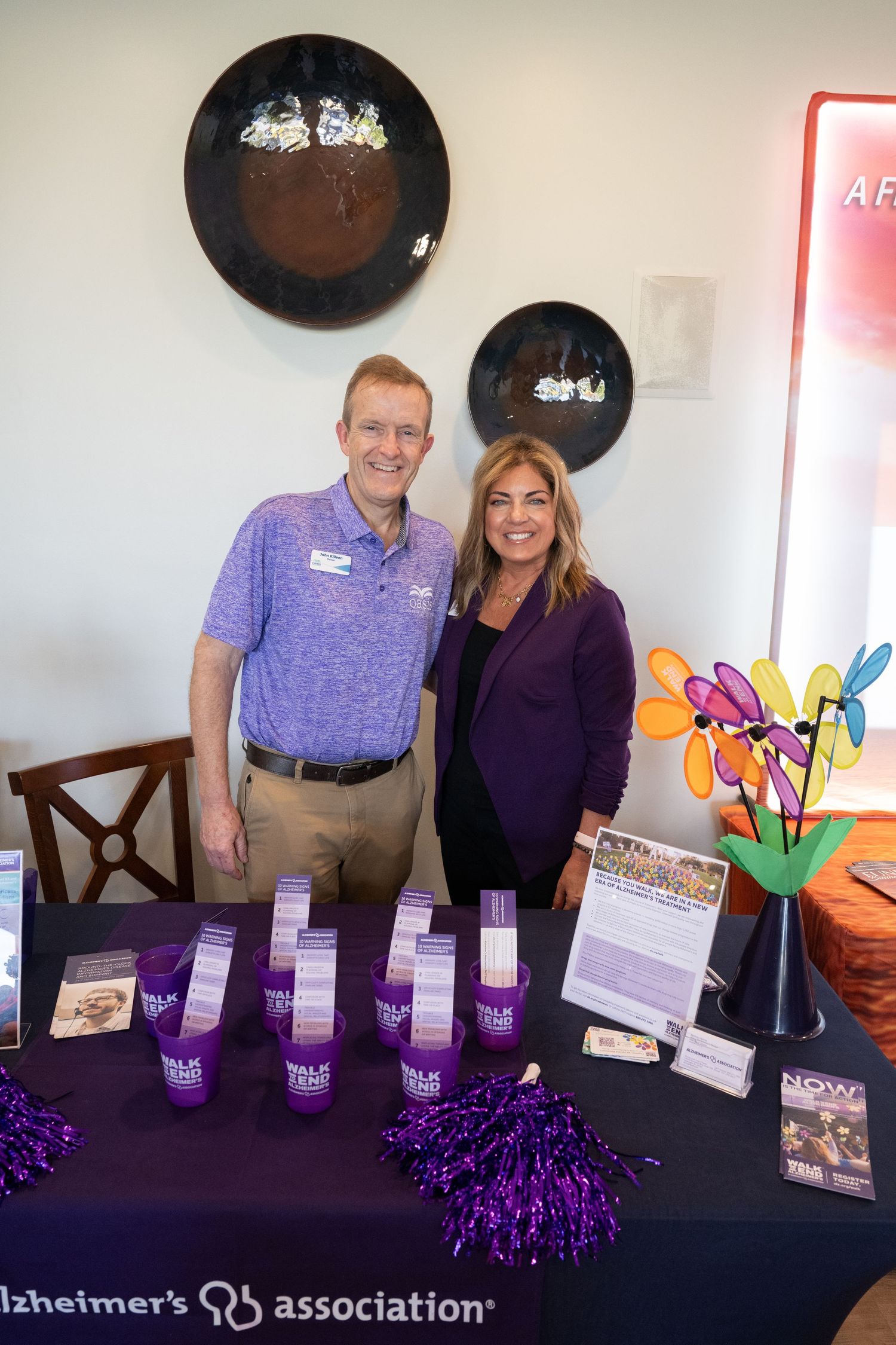 Representatives at an Alzheimer's Association information table display purple promotional materials and handouts.