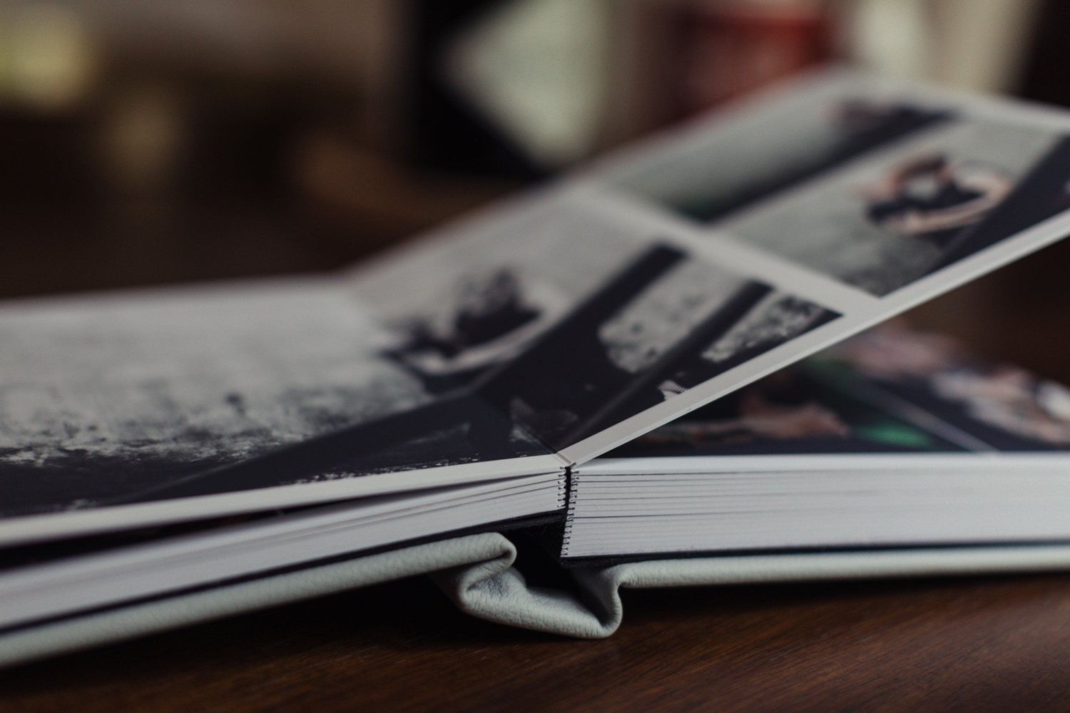 A close-up view of old photographs arranged in a photo album on a wooden surface.