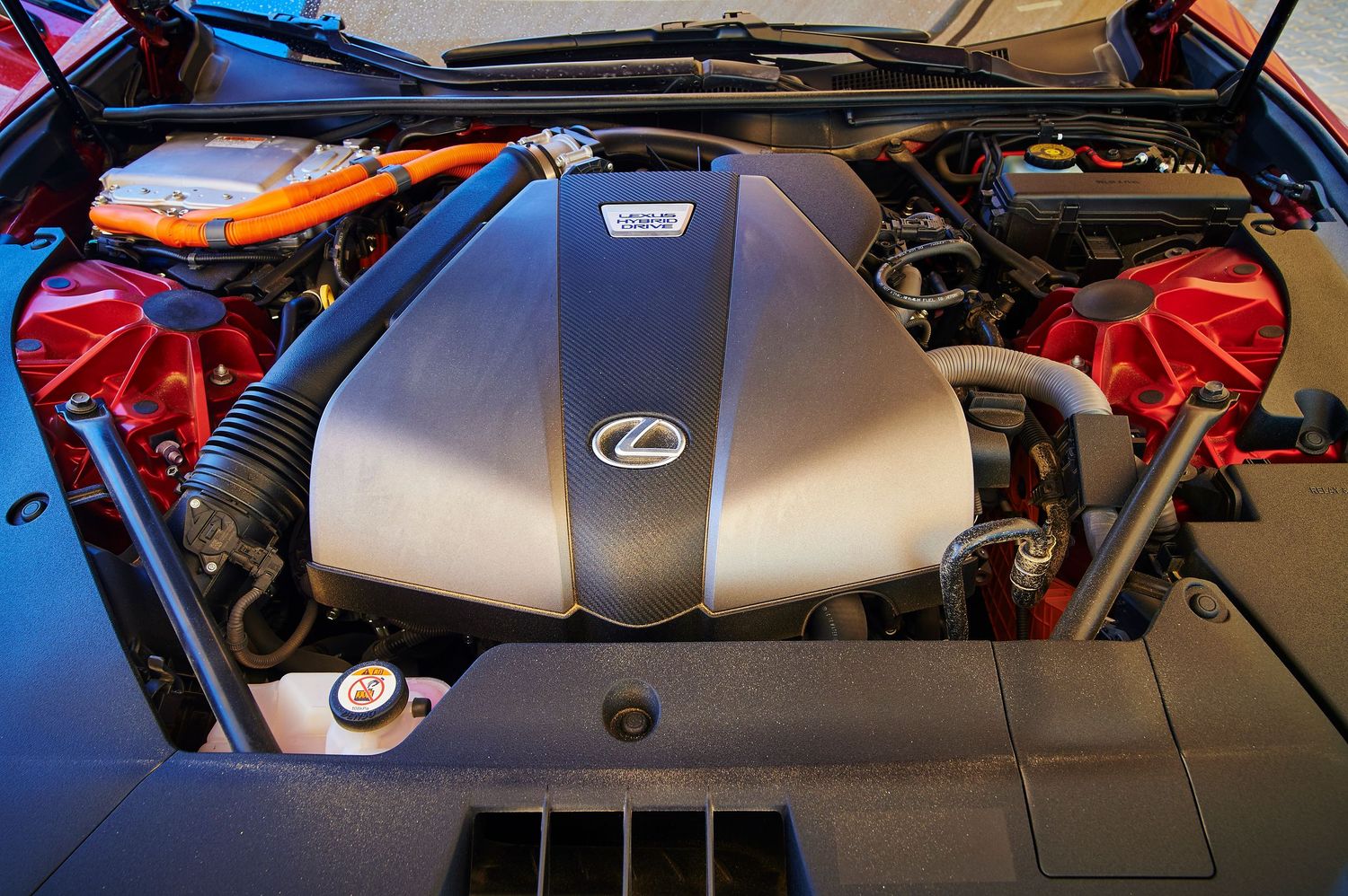 Lexus engine bay showing silver engine cover and orange hybrid components.