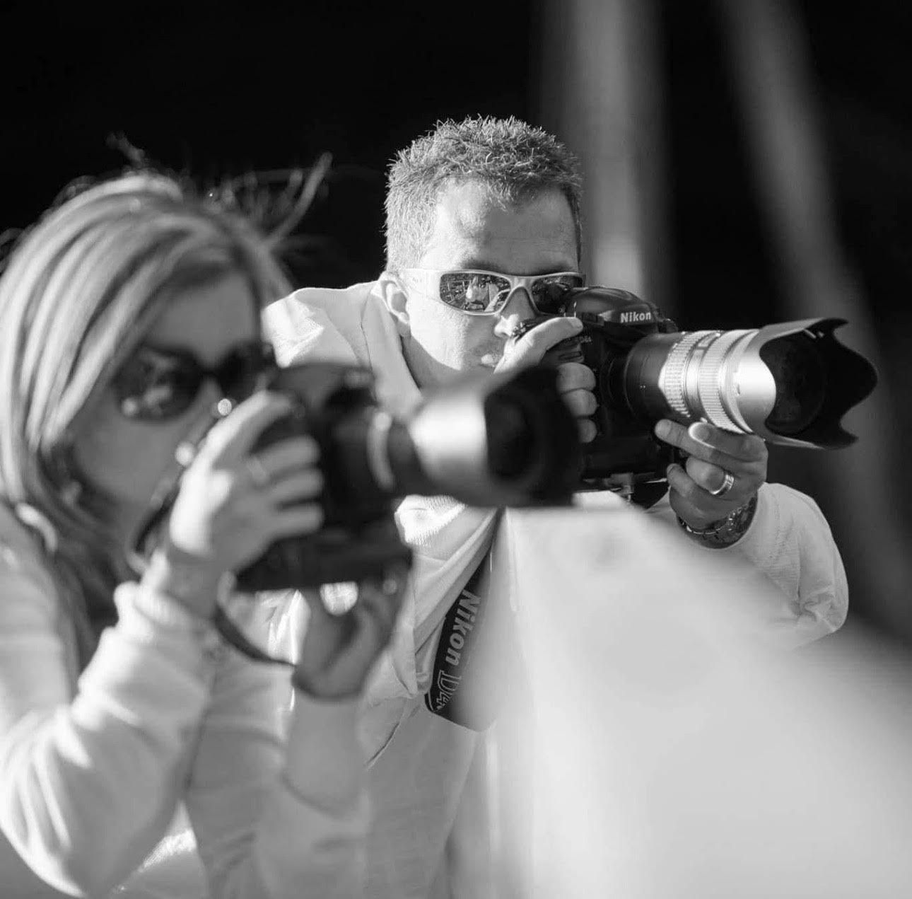 Multiple photographers with cameras in black and white composition taking photos in a row.