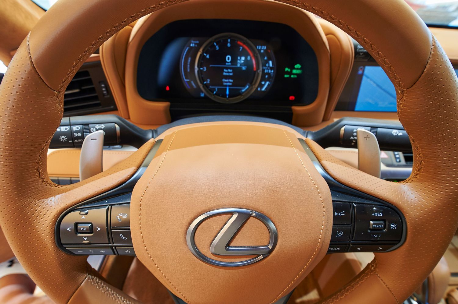 Lexus steering wheel with digital instrument cluster display and tan leather wrapping.