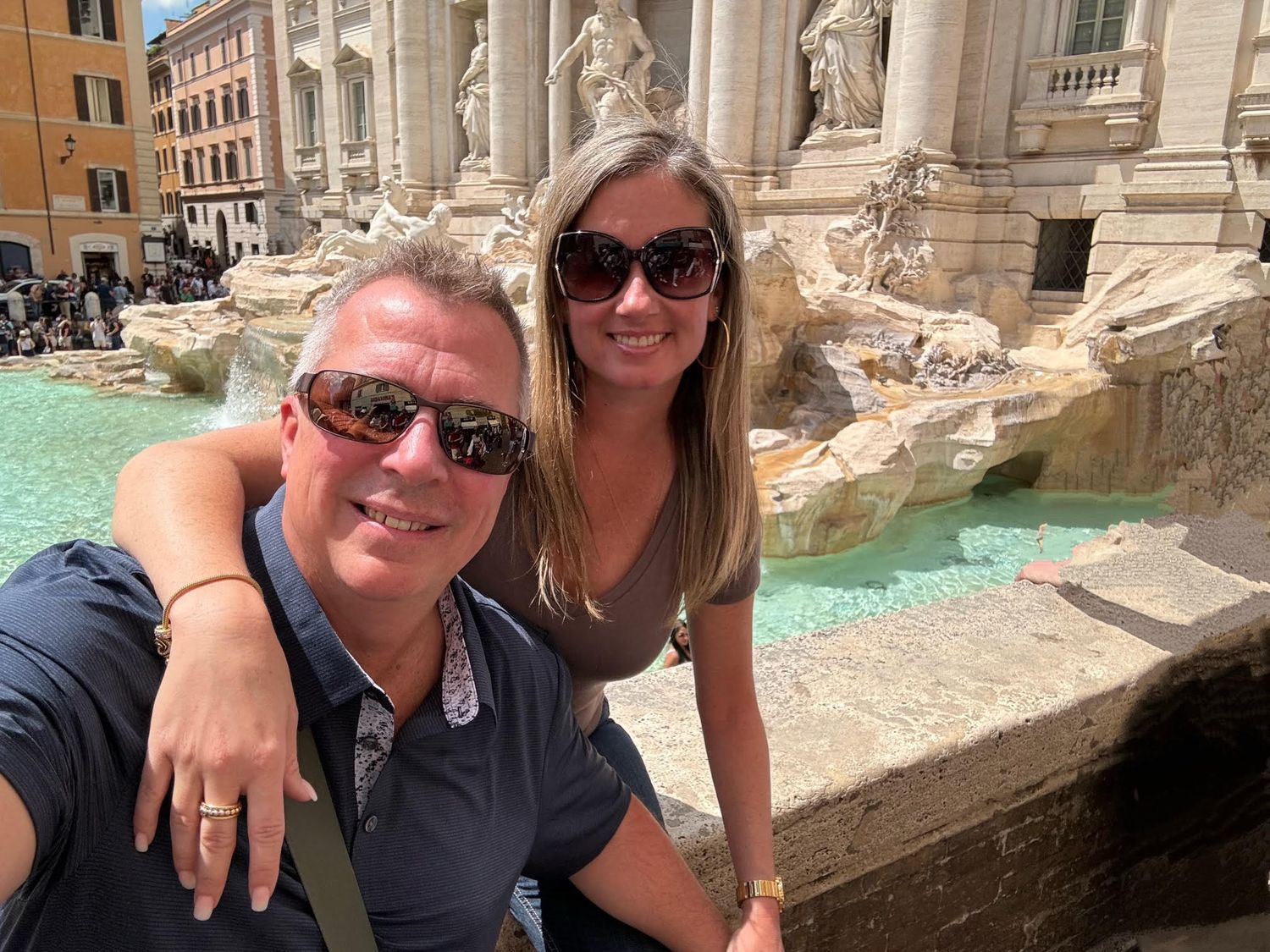 Tourists enjoying views of the iconic Trevi Fountain in Rome during daytime with its ornate Baroque architecture and blue water.