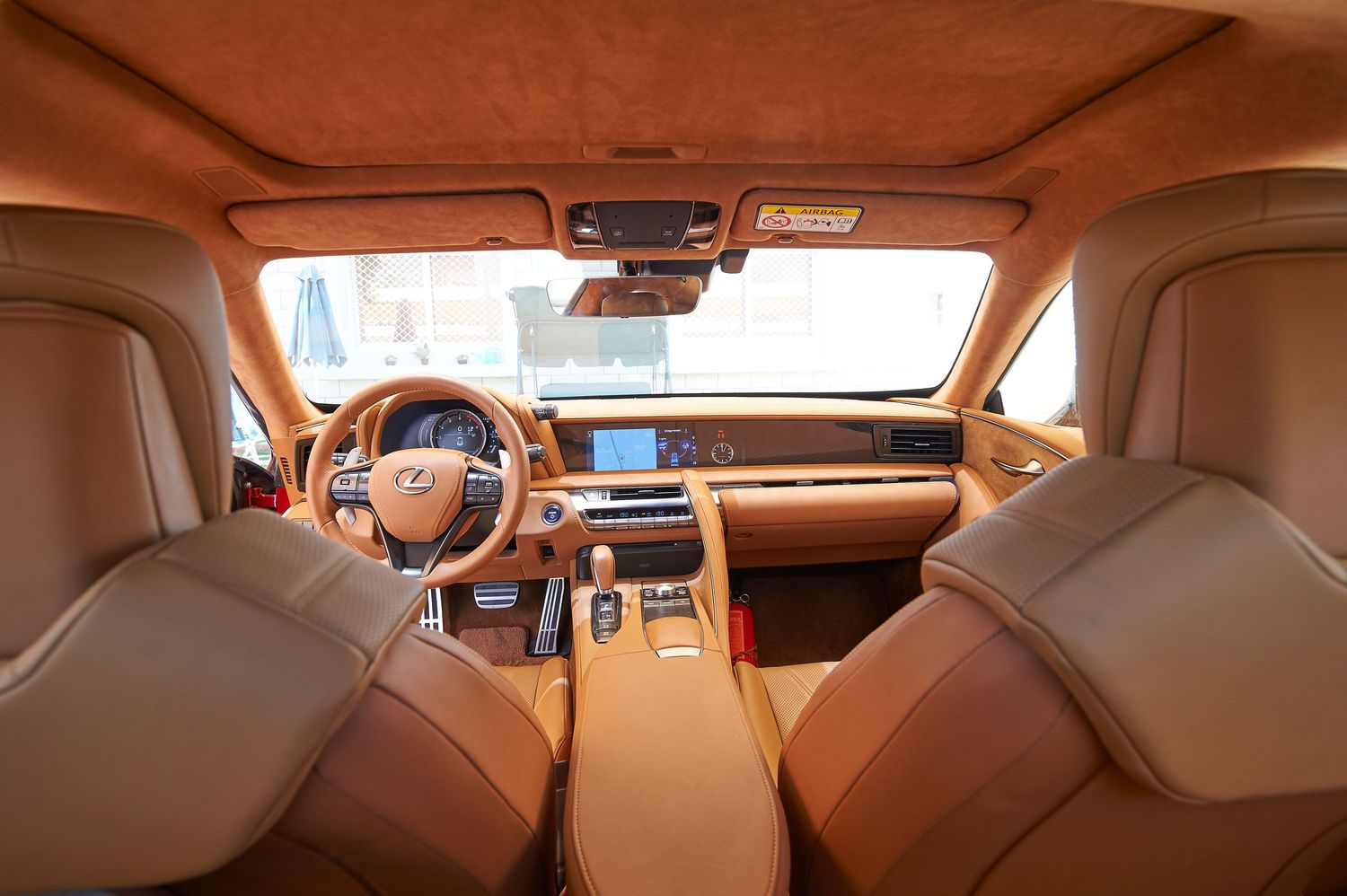 Interior panorama of luxury vehicle showing tan leather and modern dashboard design.