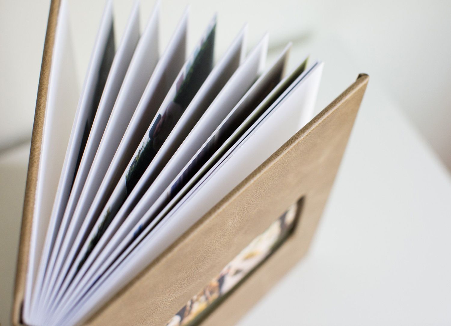 Close-up view of white paper pages fanned out inside a beige book cover with shallow depth of field.
