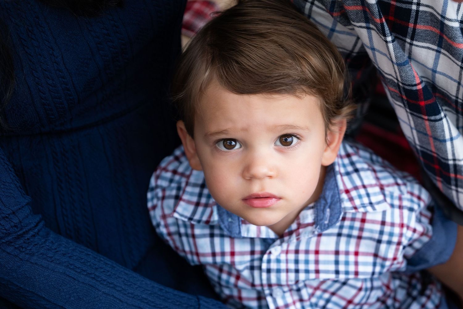 A child in a plaid shirt poses against a dark background with various expressions and angles.