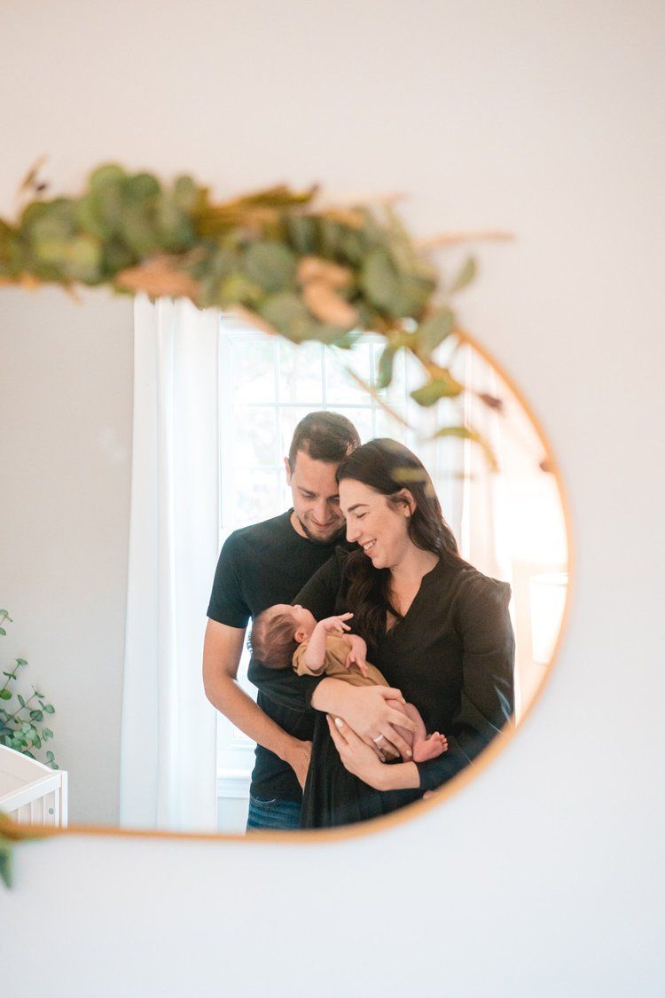 Couple sharing tender moments reflected in an oval mirror with greenery decoration.