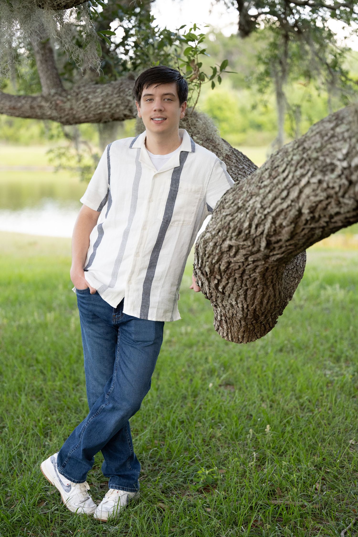 Four outdoor portrait shots showing someone in a white striped shirt and jeans leaning against a large tree trunk.