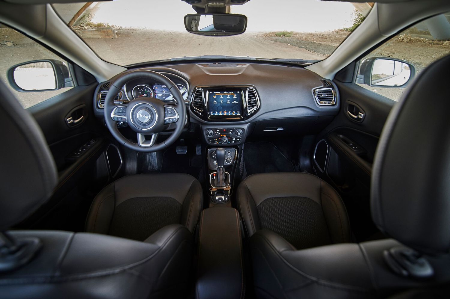 Interior view of Jeep Compass showing dashboard, infotainment system and front seats.