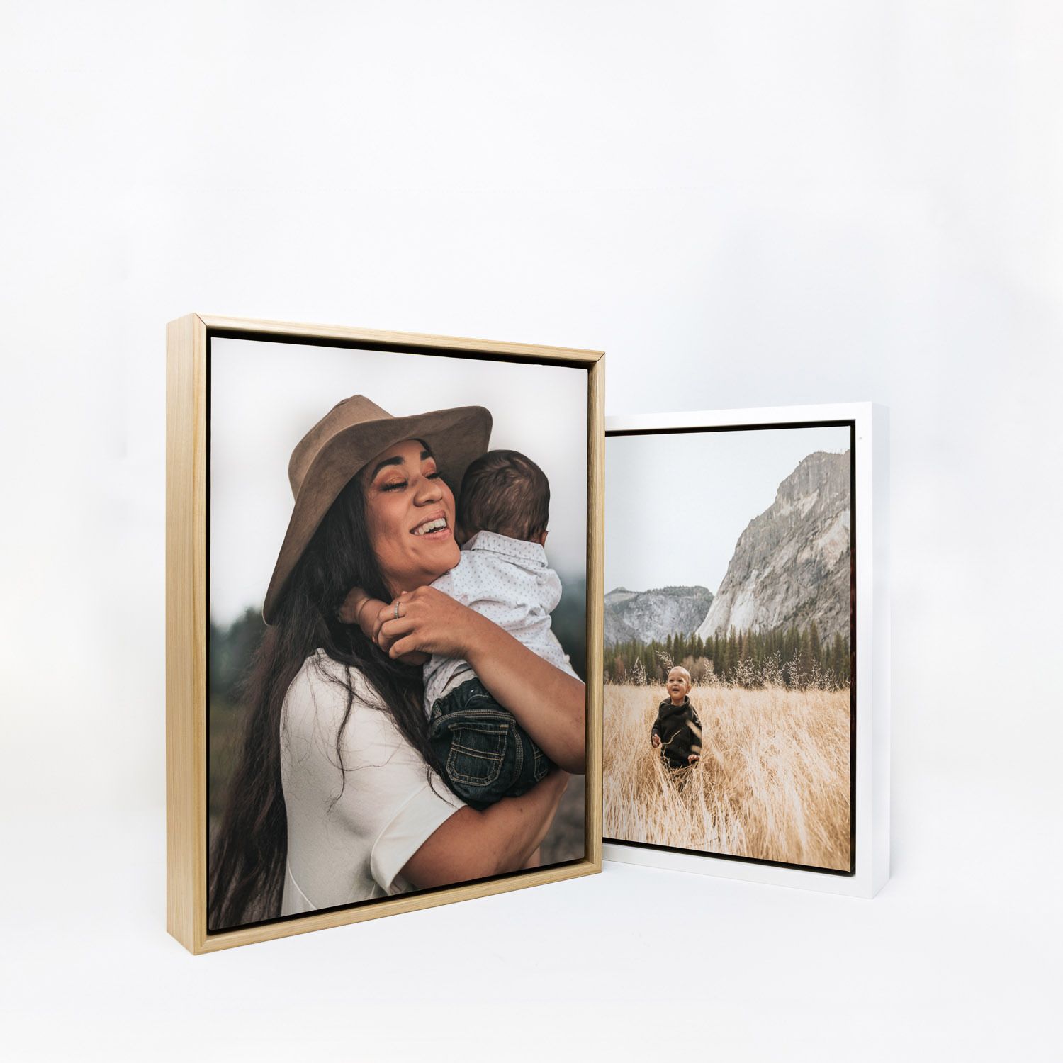 Gallery wall display featuring framed photographs of natural landscapes and portraits in light wooden frames.